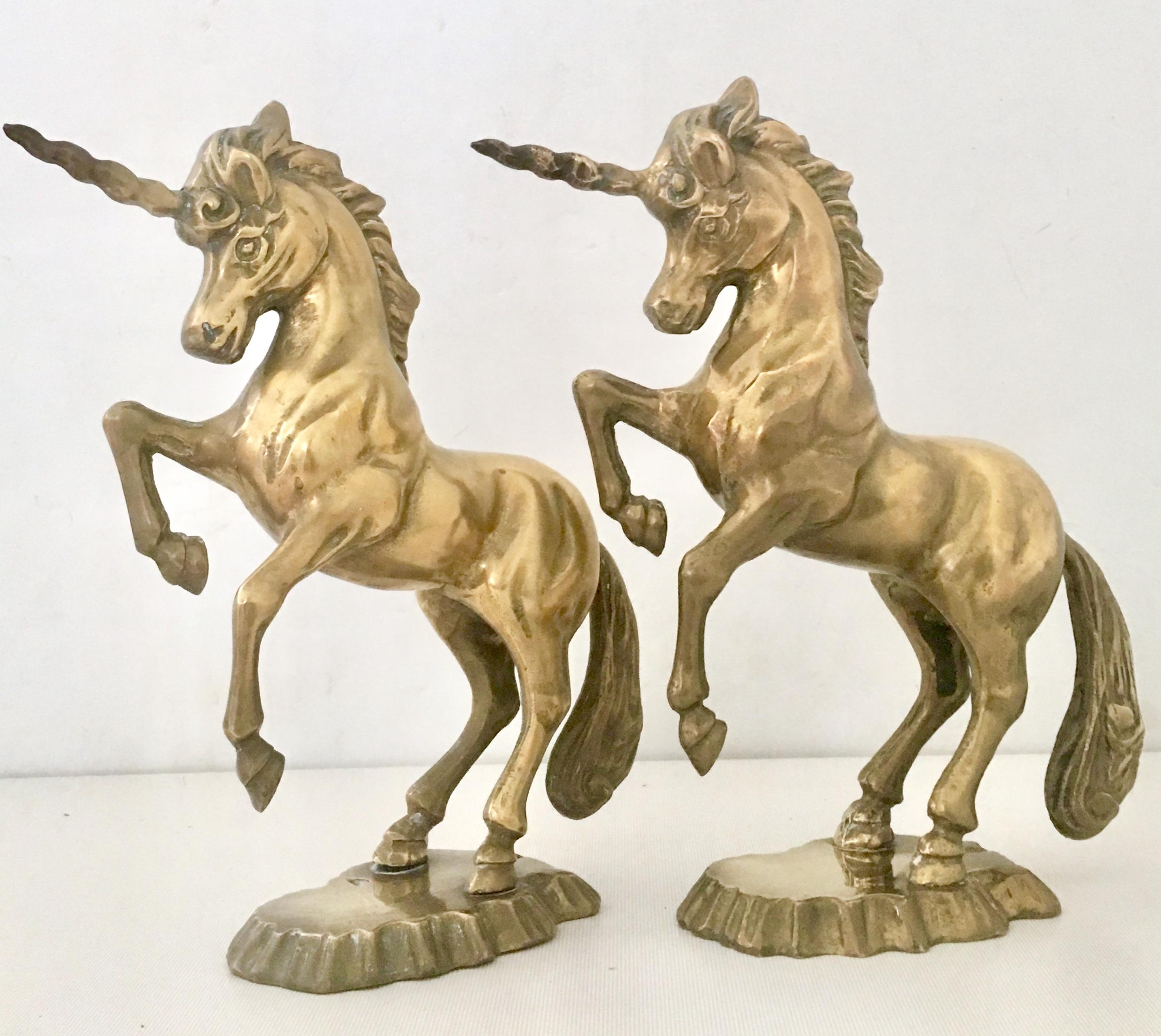 Mid-20th century pair of solid brass unicorn sculptures. These substantial polished solid brass unicorn sculptures are mounted on a abstract faux rock plateau.