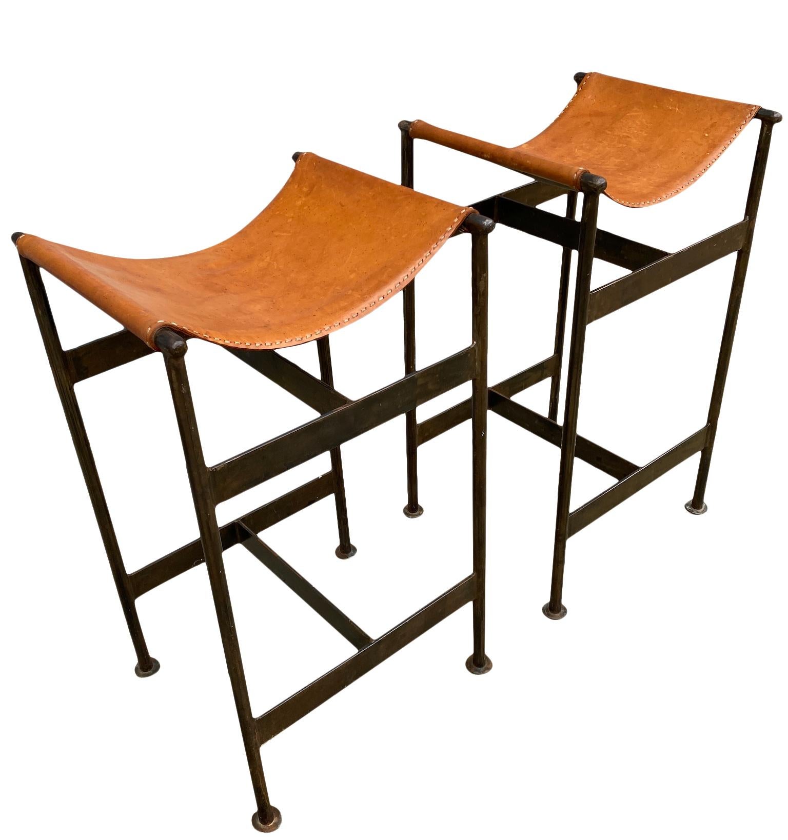 Beautiful midcentury pair of steel and leather Sling Stools style of William Katavolos. Original saddle leather on a steel frame. Leather is in original vintage condition. Steel is raw and shows rust very industrial look. Very comfortable. No
