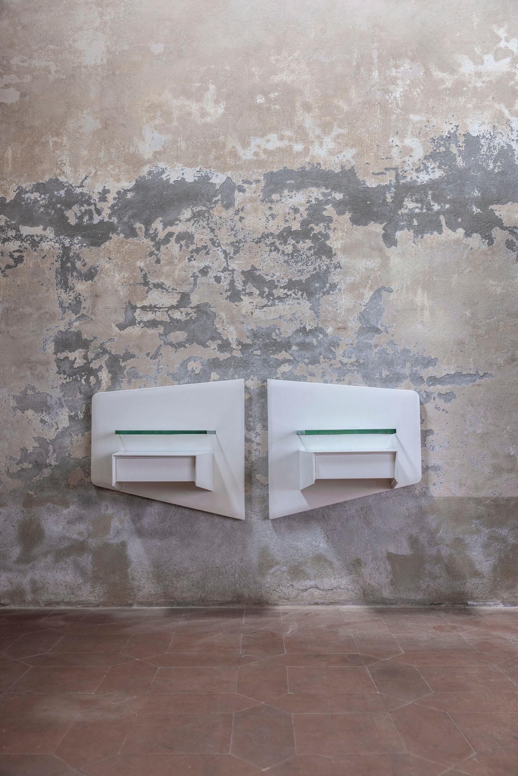 Pair of elegant Italian suspended bedside tables, attributed to Vittorio Dassi.  
Featuring a white lacquered wooden structure, each table includes two convenient drawers and a refined glass shelf. 
Italy, 1950s