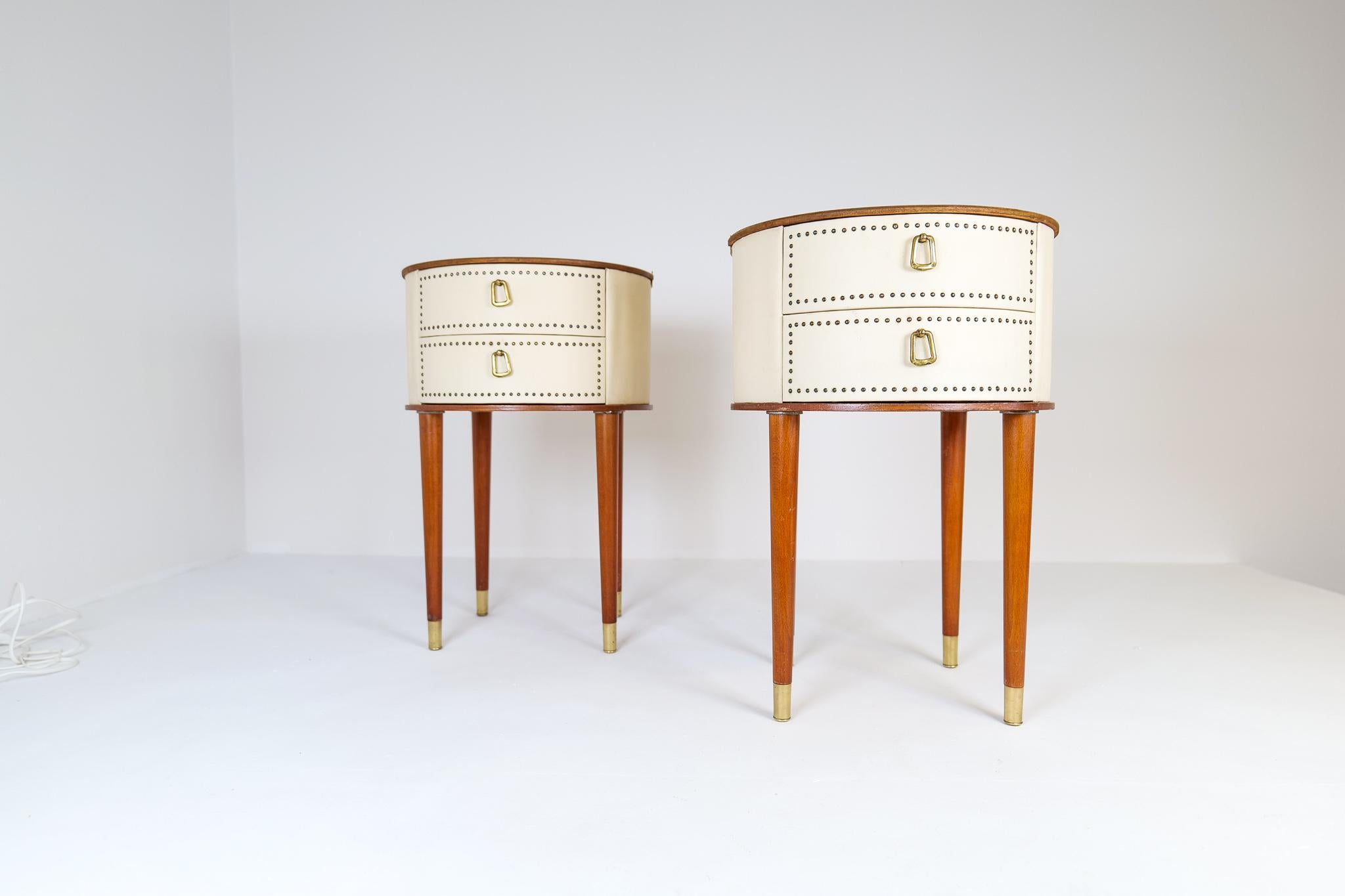 This pair of nightstands in mahogany and vinyl with a rounded half circle in patinated brass was designed by Halvdan Peterson for Tibro Mobelfabrik in the early 1950s Sweden. 

Good vintage condition, with refinished top. Marks and wear are