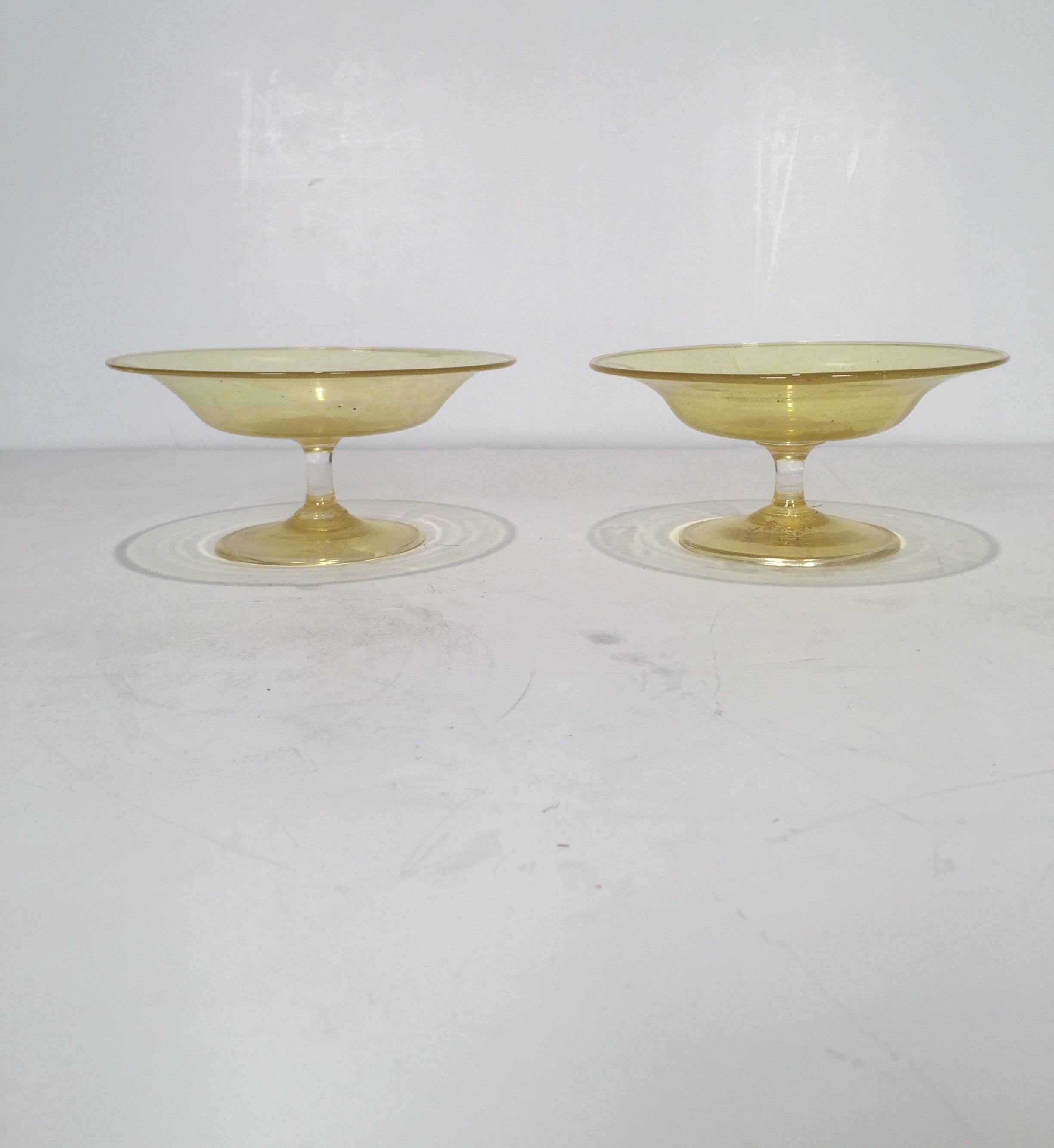 A pair of yellow amber with gold flecks hand blown Venetian glass compotes. Simplistic form with yellow base glass with gold flecks throughout, Italy, 1950s. Measures: 7 inches in diameter.