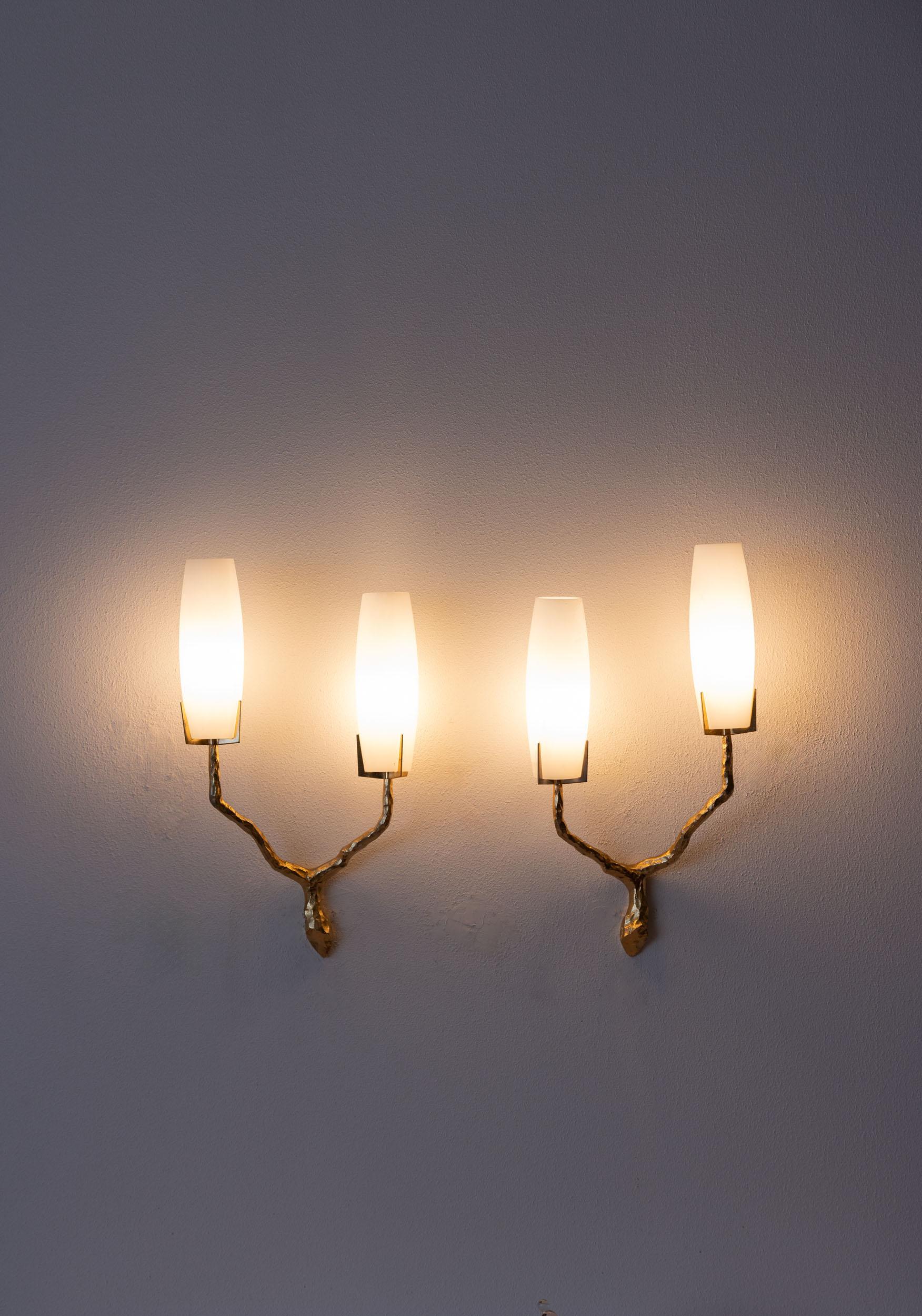 Midcentury set of two wall lamps by Maison Arlus.
Stunning set of two golden bronze wall lights with opaline glass shades. Each lamps has two-arm branch.
Based on a drawing by Felix Agostini and manufactured by Maison Arlus, France in the