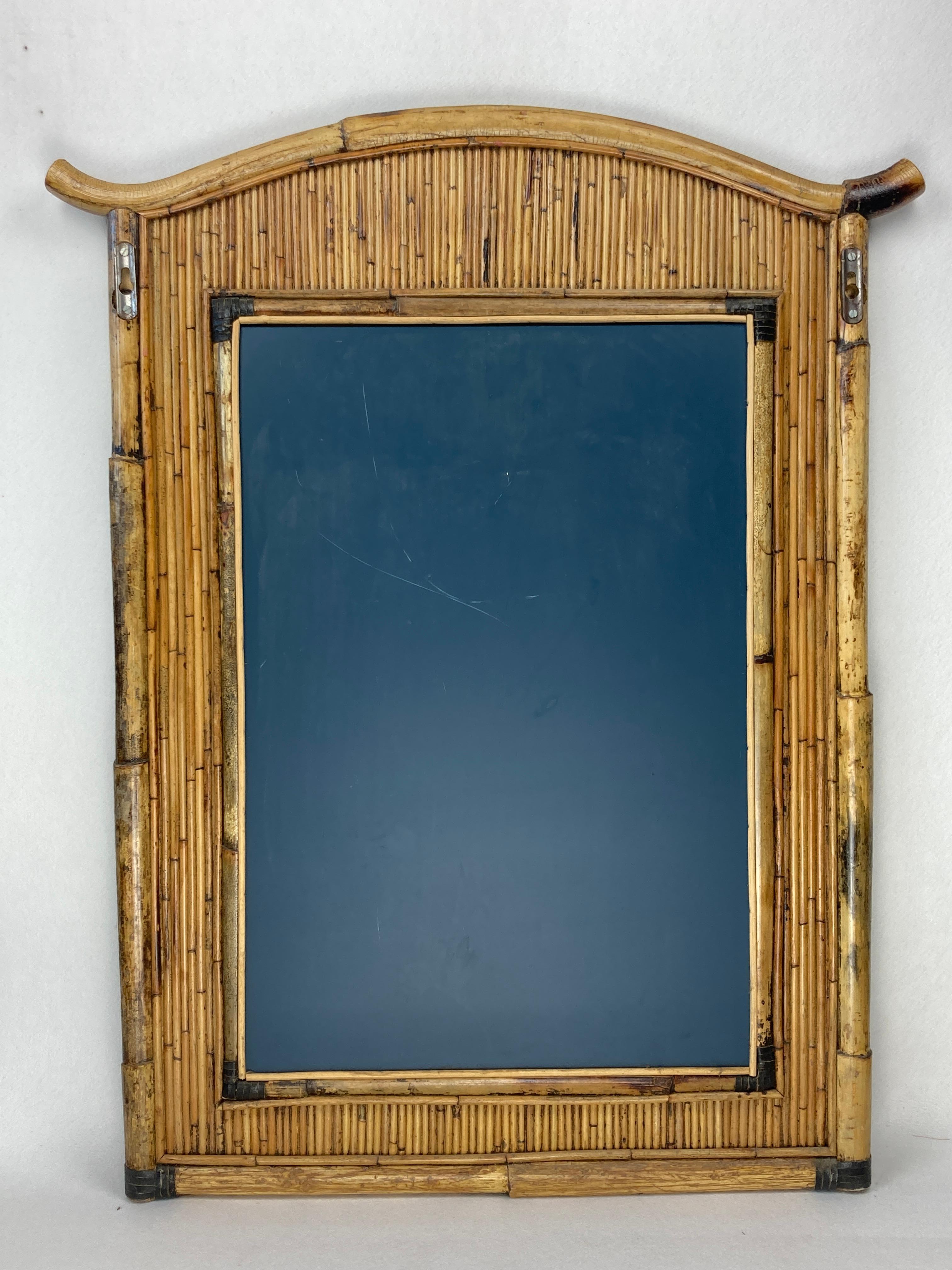 Un meraviglioso specchio in rattan di bambù Palm Regency della metà del secolo scorso. Questo raro specchio risale agli anni '60 circa e ha una dimensione di 100 cm per 80 cm misurata dal punto più largo. Lo specchio in vetro misura circa 68 cm per