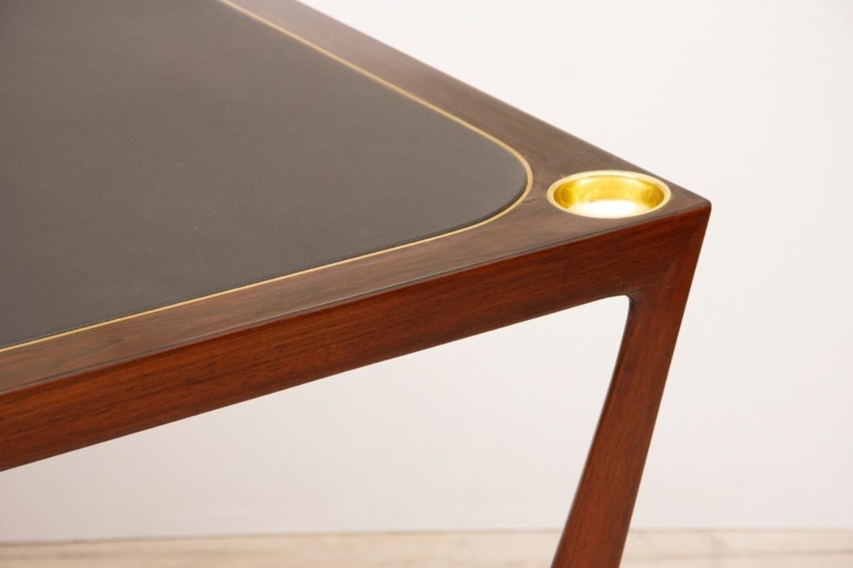 An Italian midcentury card table designed by Paolo Buffa made in rosewood with beautifully carved legs and cross stretcher. Black leather playing surface and brass sunken counter wells.