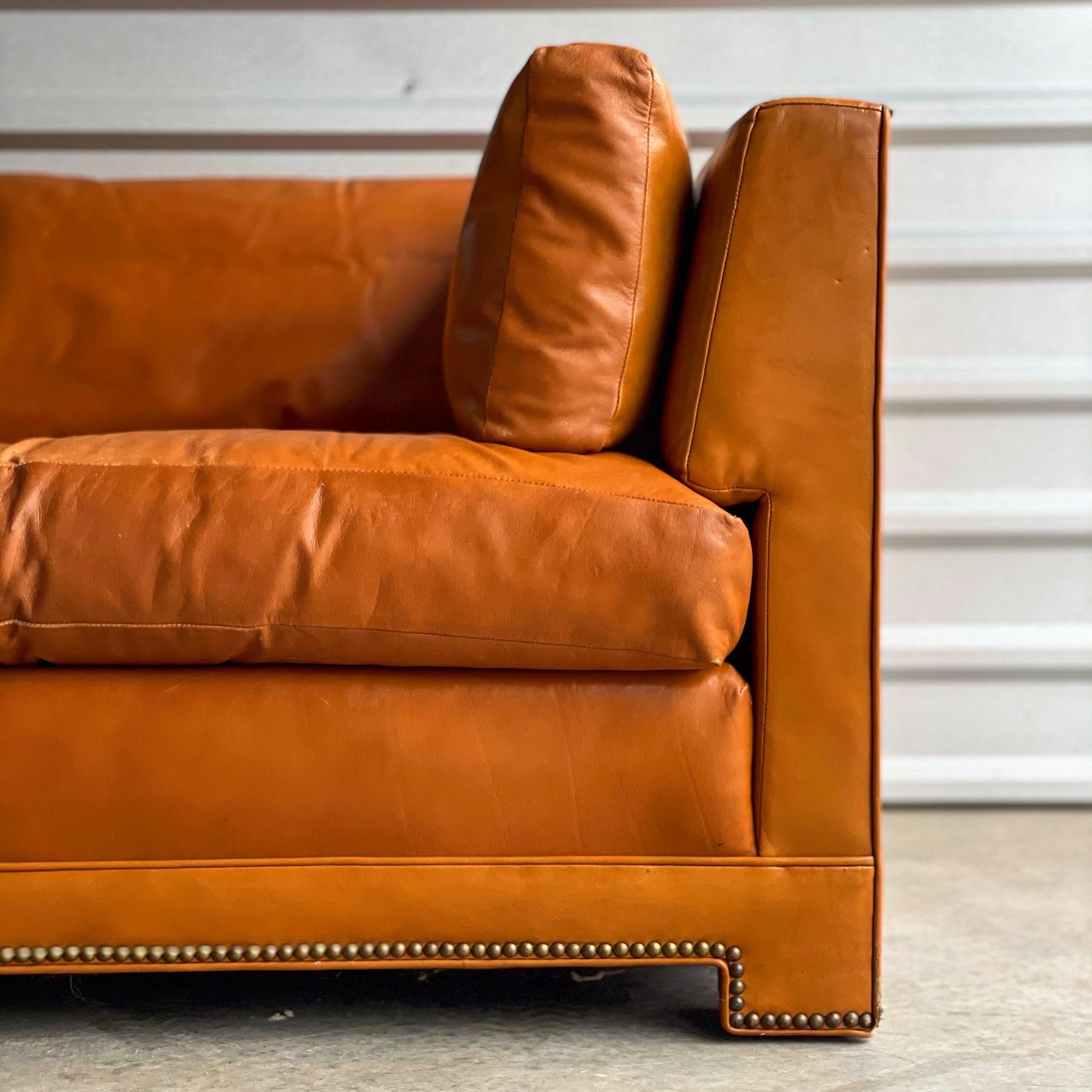 Rare and stunning Parsons style sofa by John Widdicomb. Built to stand the test of time, Widdicomb spared no expense on materials and craftsmanship. Goose down filled cushions, all original cognac tone leather and brass nail head detail. Leather is