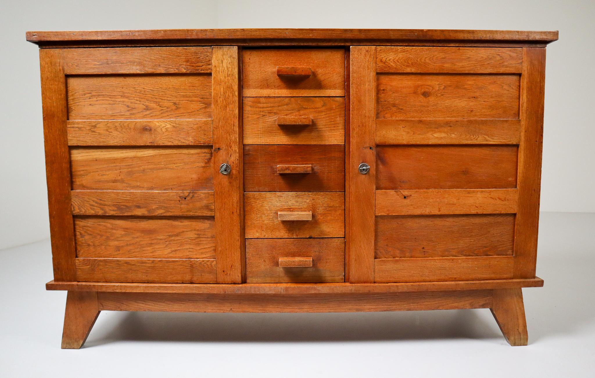 Midcentury sideboard in patinated French oak. Published in 1944 and designed by René Gabriel, this sideboard dates back to the 1950s and is a typical example of so-called reconstruction furniture. Emergency product for the victims of the war, the