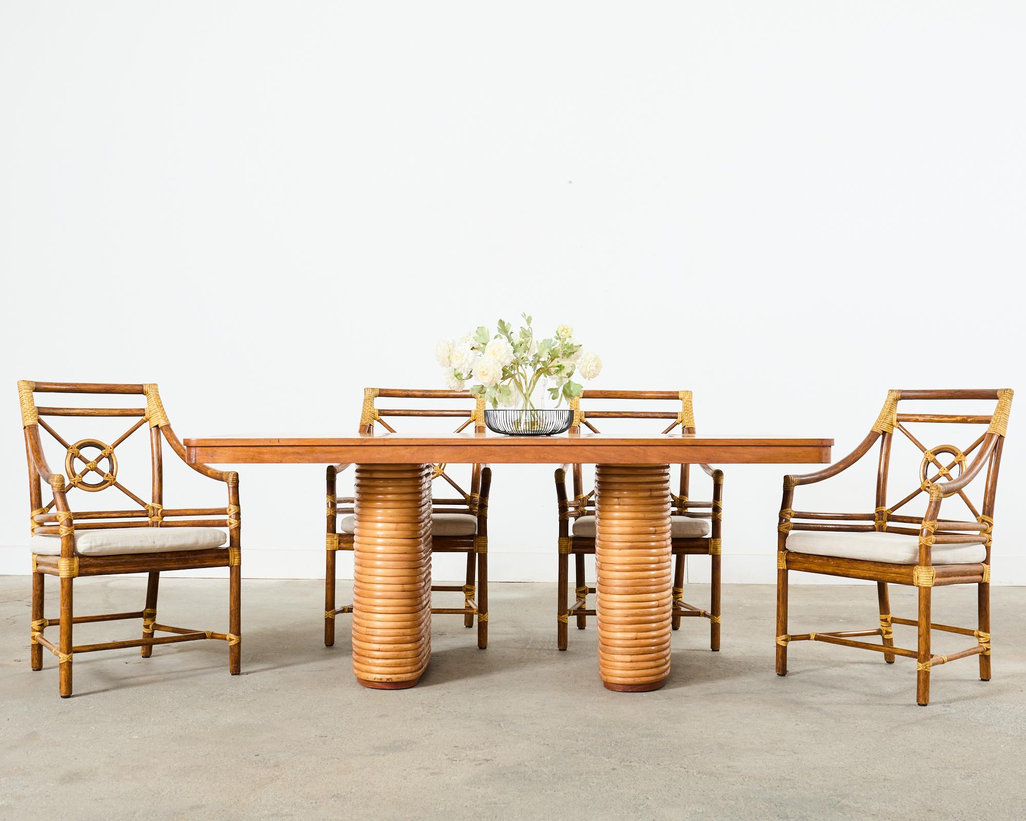 Distinctive mid-century modern hardwood dining table made in the manner and style of Paul Frankl. The table features an iconic profile of double stacked rattan pedestals supporting a rectangular hardwood top. The top is 3 inches thick with a warm