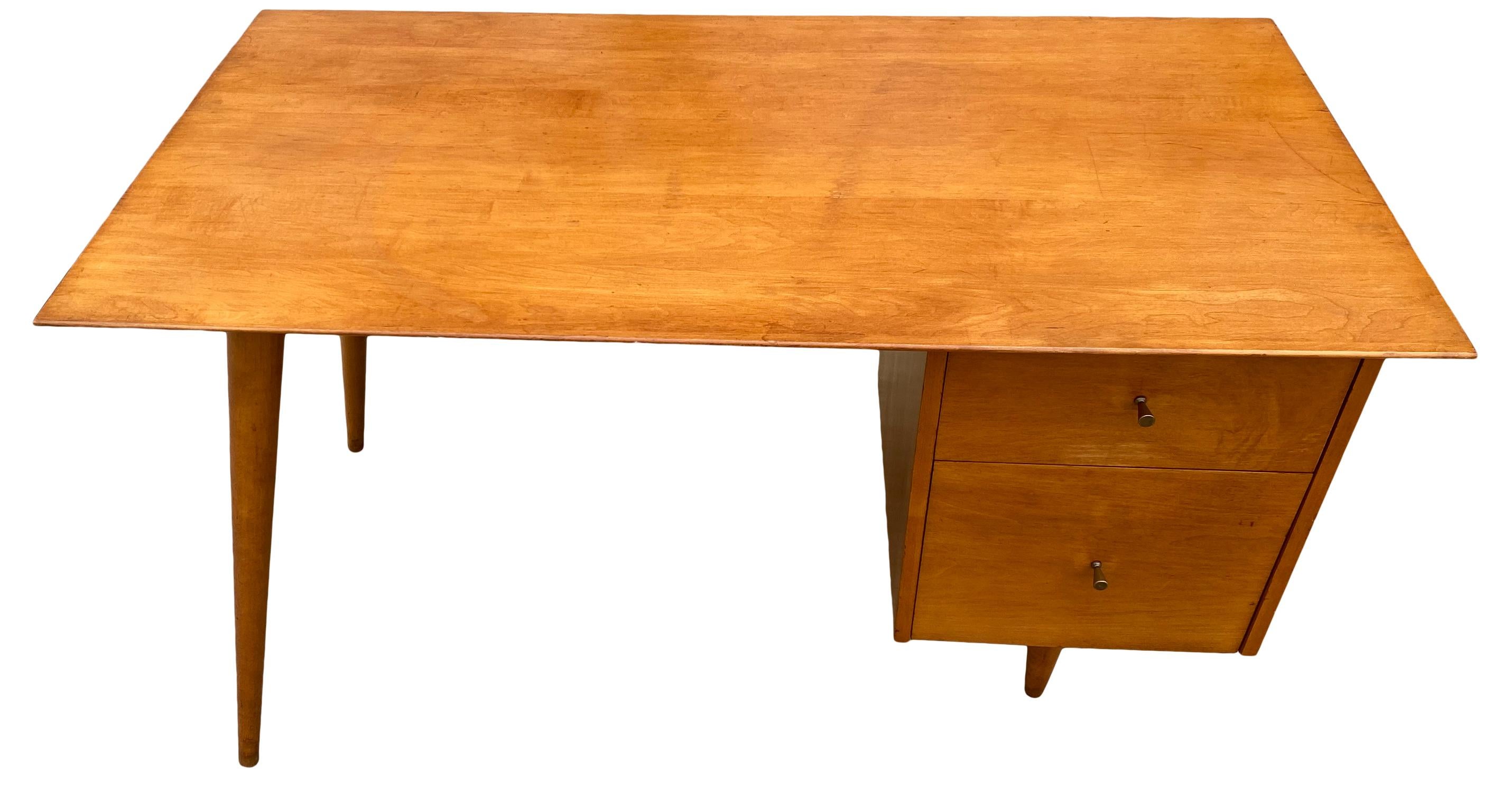 Beautiful Paul McCobb Planner Group #1560 double drawer desk Tobacco maple finish with brass knobs solid maple. Desk is in great original vintage condition. Very beautiful designed desk on tapered legs - all solid maple. All legs unscrew. Drawers