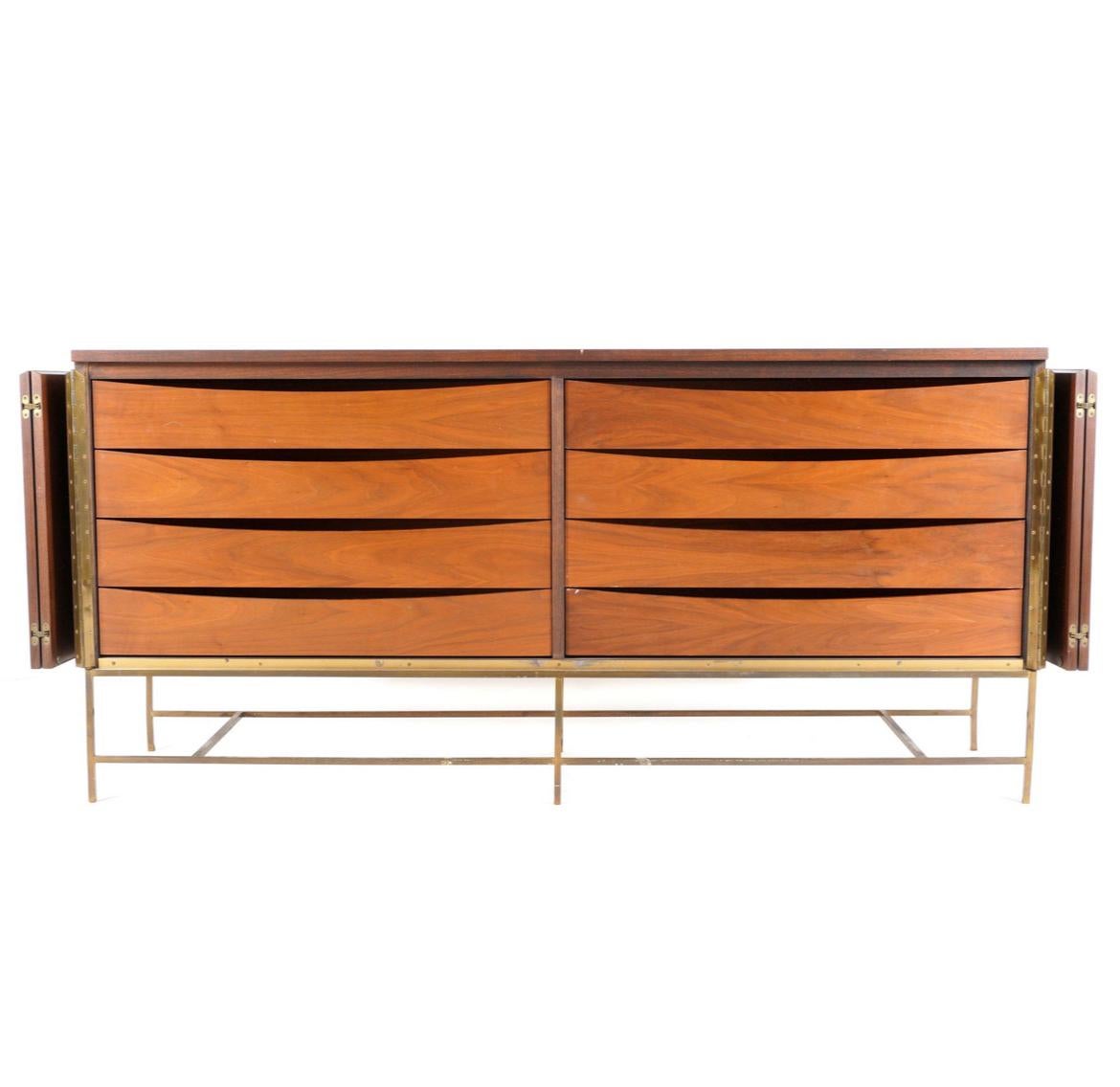 Midcentury American designer Paul McCobb 8-drawer dresser credenza in walnut. Original finish in good vintage condition with front folding walnut front doors and brass accents. All walnut with a brass base. Has (8) drawers total all of them are