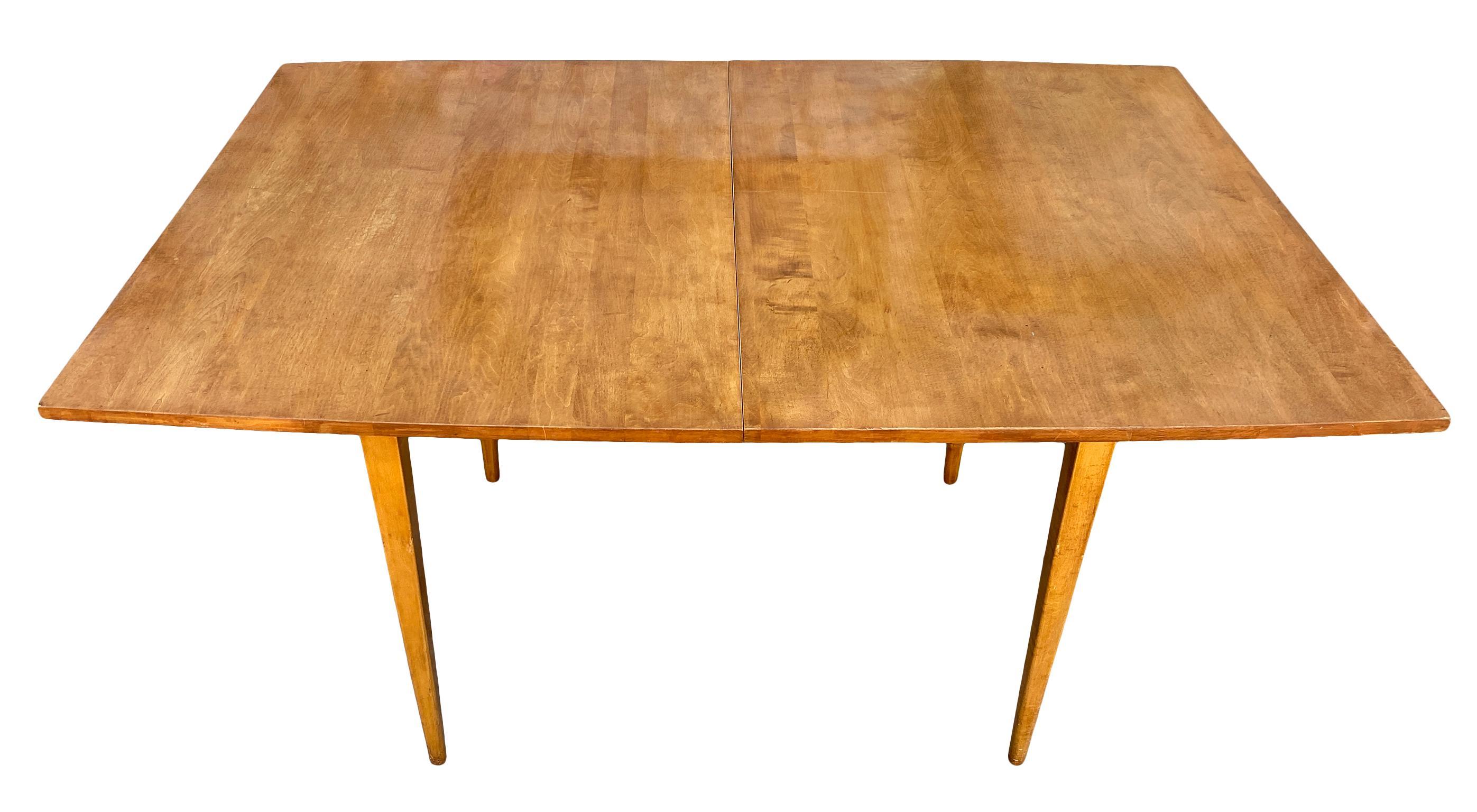Magnifique table de salle à manger à rallonge en érable massif de Paul McCobb du début des années 1950, reposant sur 4 pieds fuselés carrés. Magnifique table en érable massif avec une légère conicité à chaque extrémité qui a une finition blonde