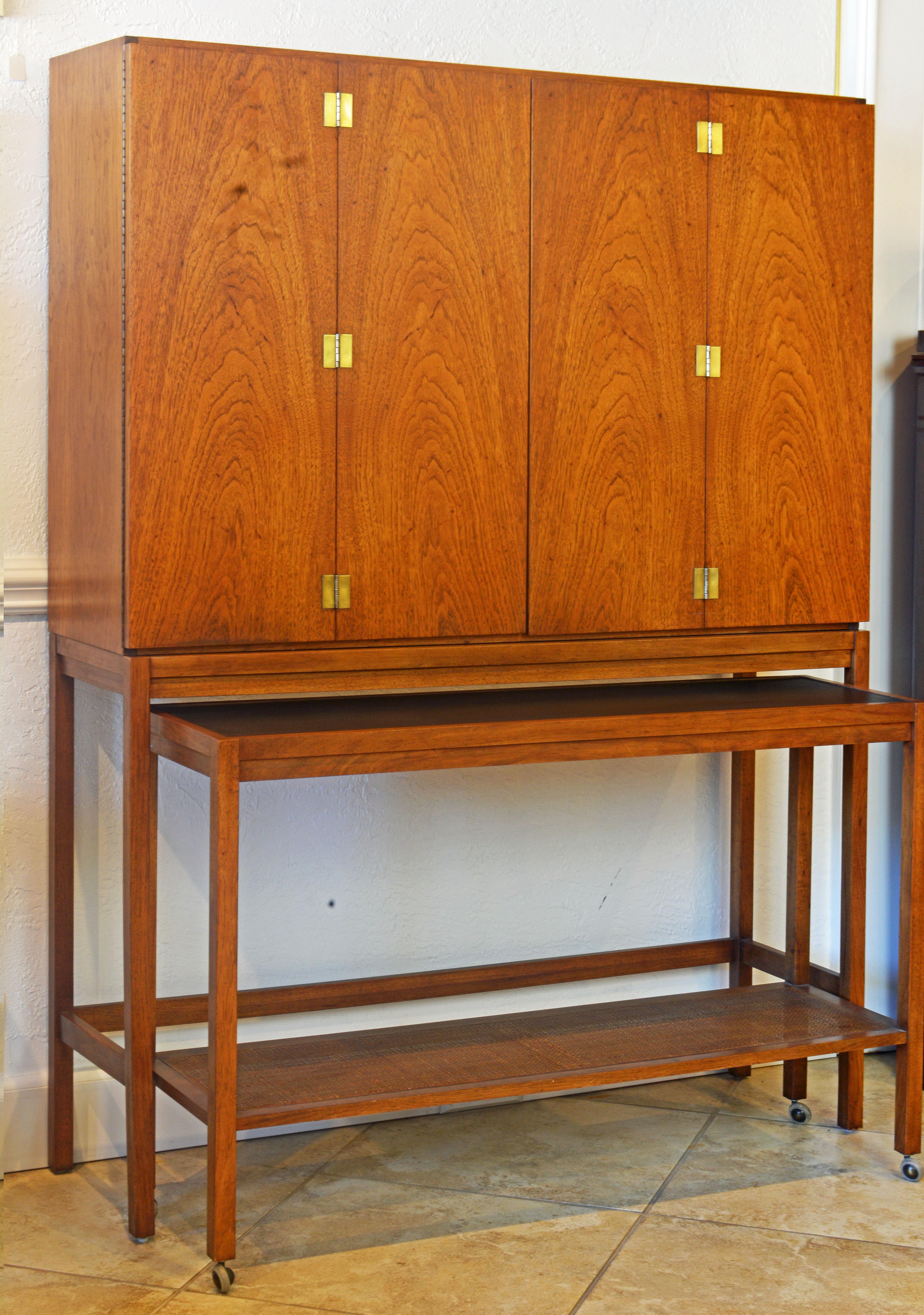 This exquisite walnut bar cabinet features four bifold doors opening up to a glass shelved interior flanked by wood shelved sections. All shelves are adjustable. The central section has light under the top. The cabinet sits on a console fitted with