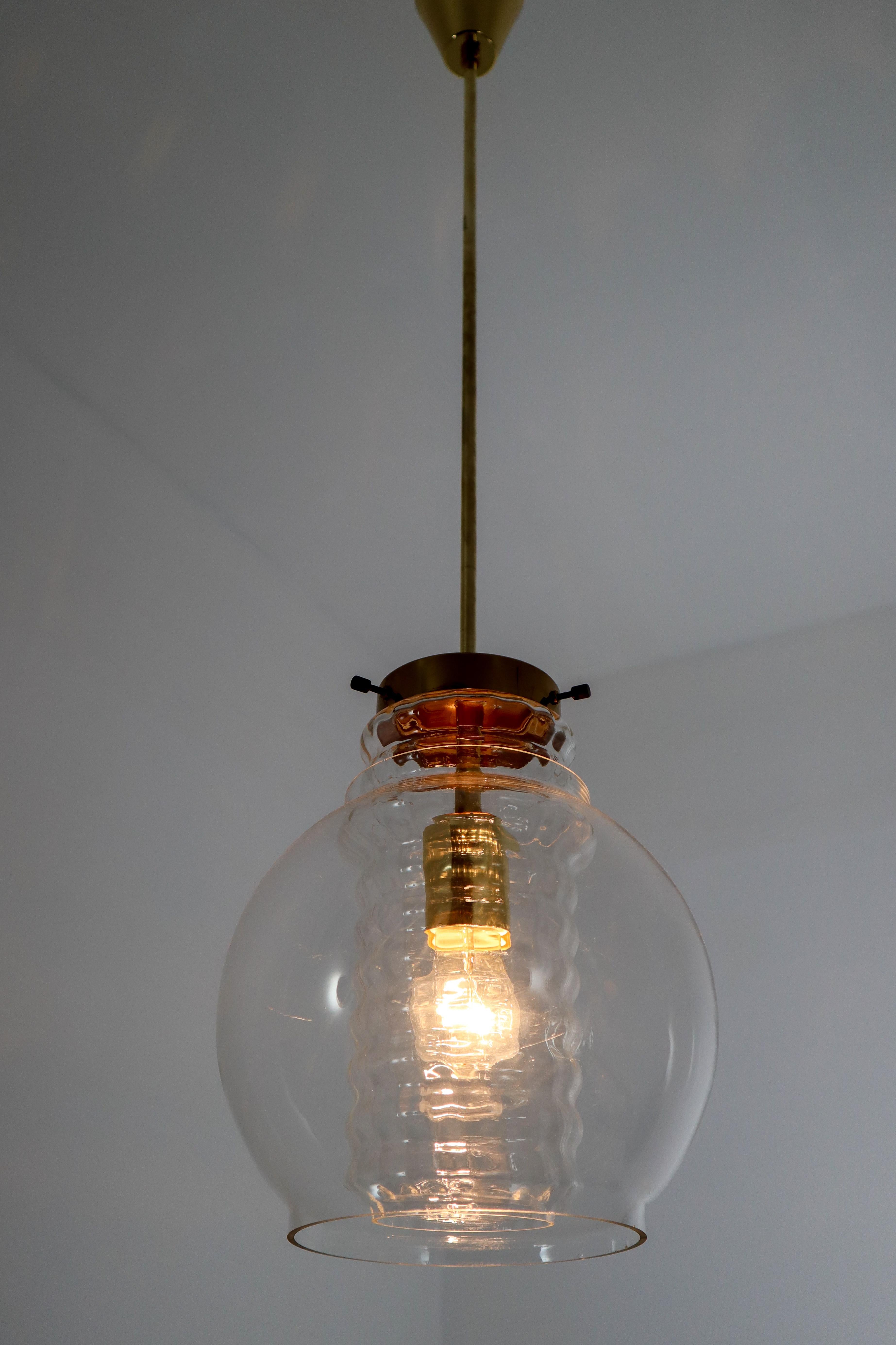 Midcentury pendants with clear glass and brass Europe 1960s. The brass fixture beautifully combines with the clear glass. Due their materials and size, these lights will create a beautiful light-partition. Perfect original condition with a small