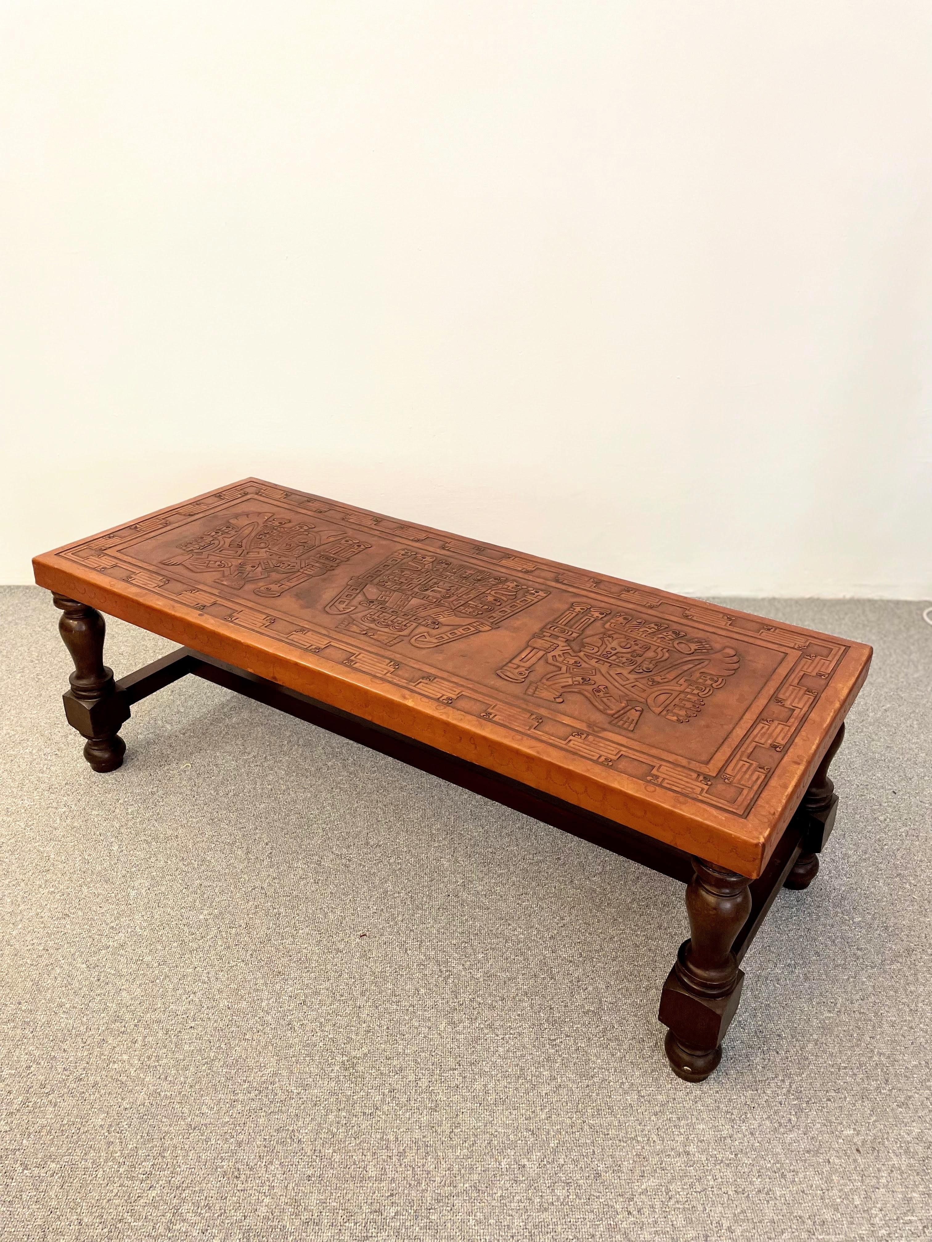 Vintage midcentury coffee table with Aztec motif on the leather top. Designed in the style of Angel Pazmino. Handmade construction in good vintage condition. The leather top has signs of wear.