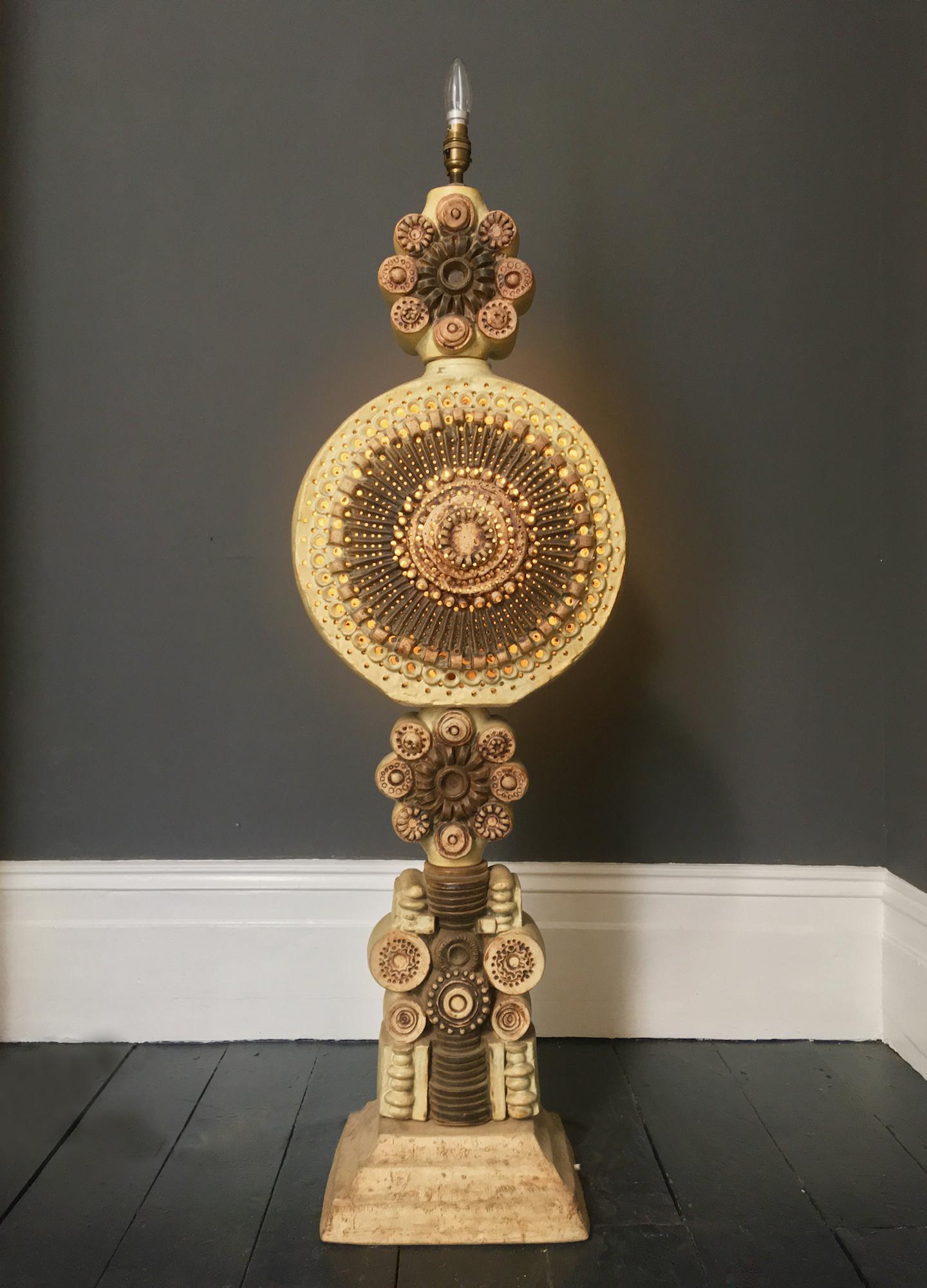 A monumental ceramic TOTEM floor lamp with pierced detail by Bernard Rooke, England, 1970s.

An impressive sculptural piece, made up of cast ceramic elements in warm neutral tones of natural stone, wheat and earth-brown, on a metal tube. The