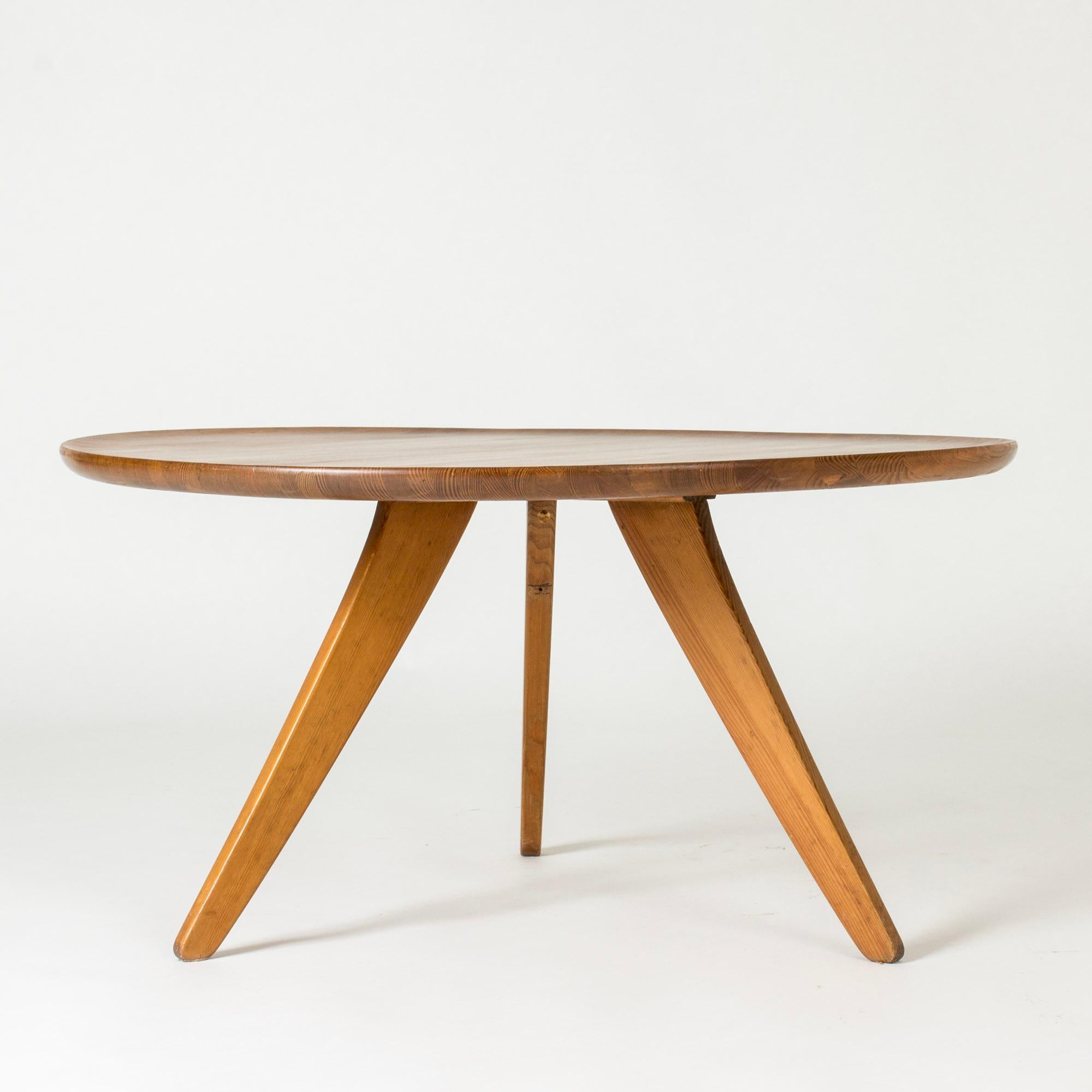 Sleek round coffee table by Carl Malmsten, made from pine. Tripod base, table top with slightly upturned edge.