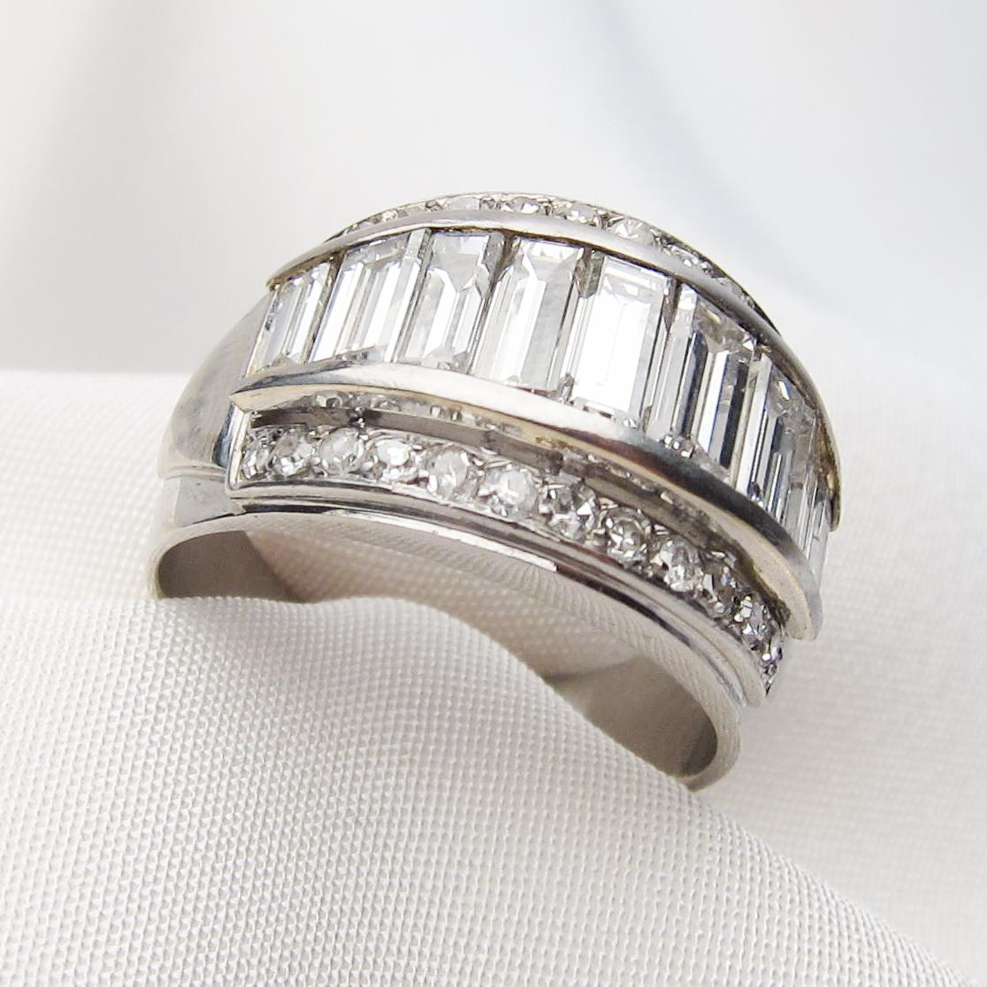 This amazingly decadent midcentury platinum band features nine beautiful baguette diamonds channel-set across the top of the ring, tapering in size with the largest in the center. Bead-set across each outside edge of the band are 13 single-cut