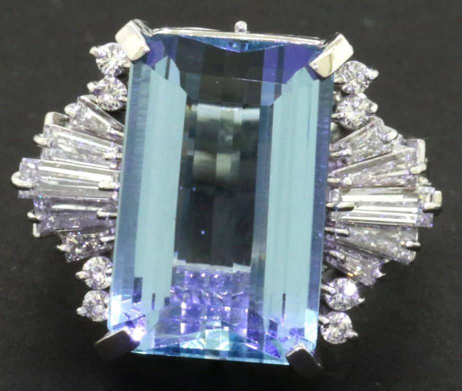 This extraordinary piece of jewelry is crafted in gorgeous platinum and features a genuine emerald cut aquamarine measuring approximately 13.94 carats (17.7 X 11.5mm).  Surrounding the central gemstone are 18 Round/Baguette cut diamonds (VS-2 to