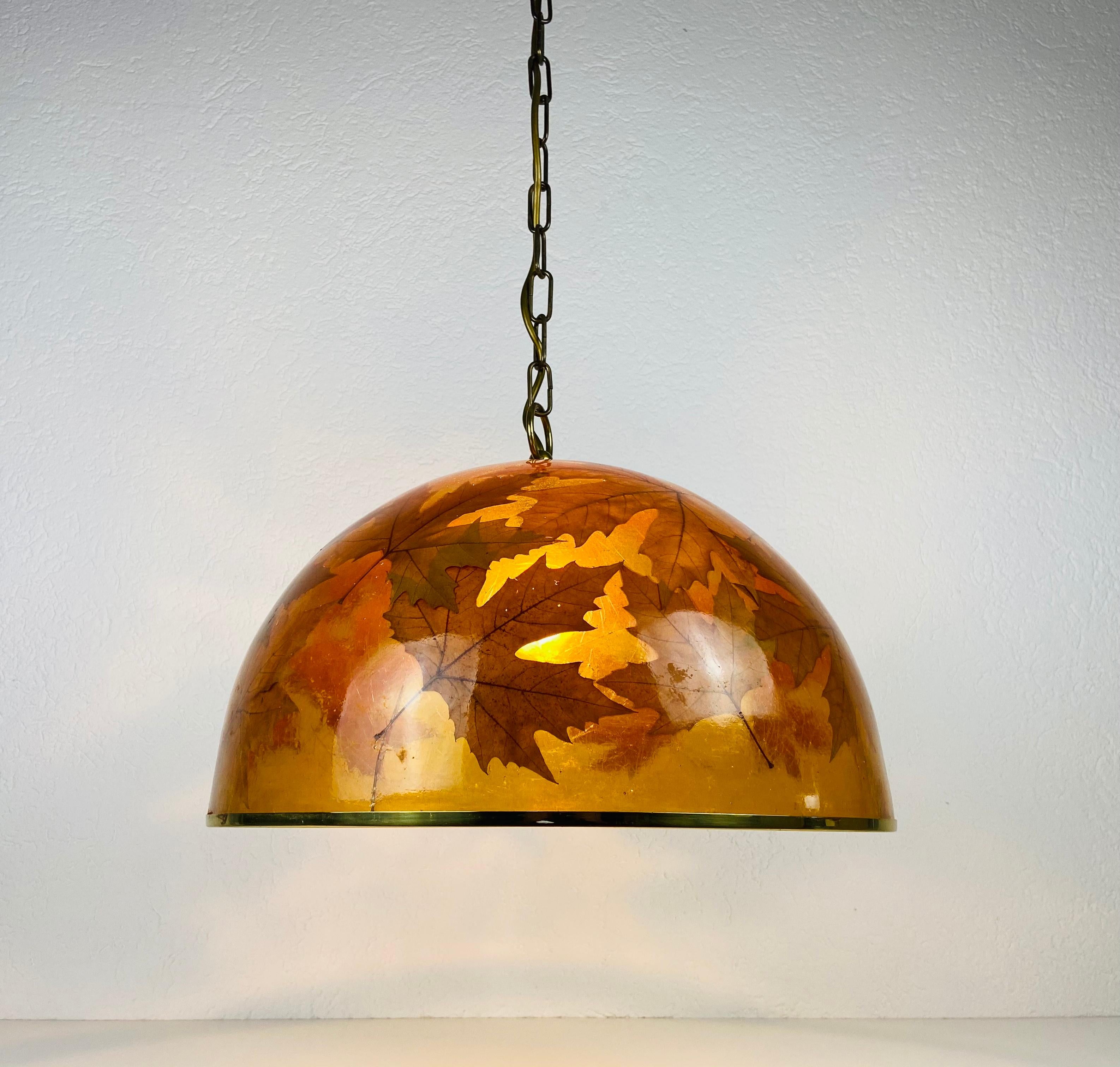 Mid-Century Modern plexiglass pendant lamp made in the 1960s. It has a beautiful design with real leaves in the plexiglass. The lamp is in good vintage condition. It has only a very small crack which is not visible when the light