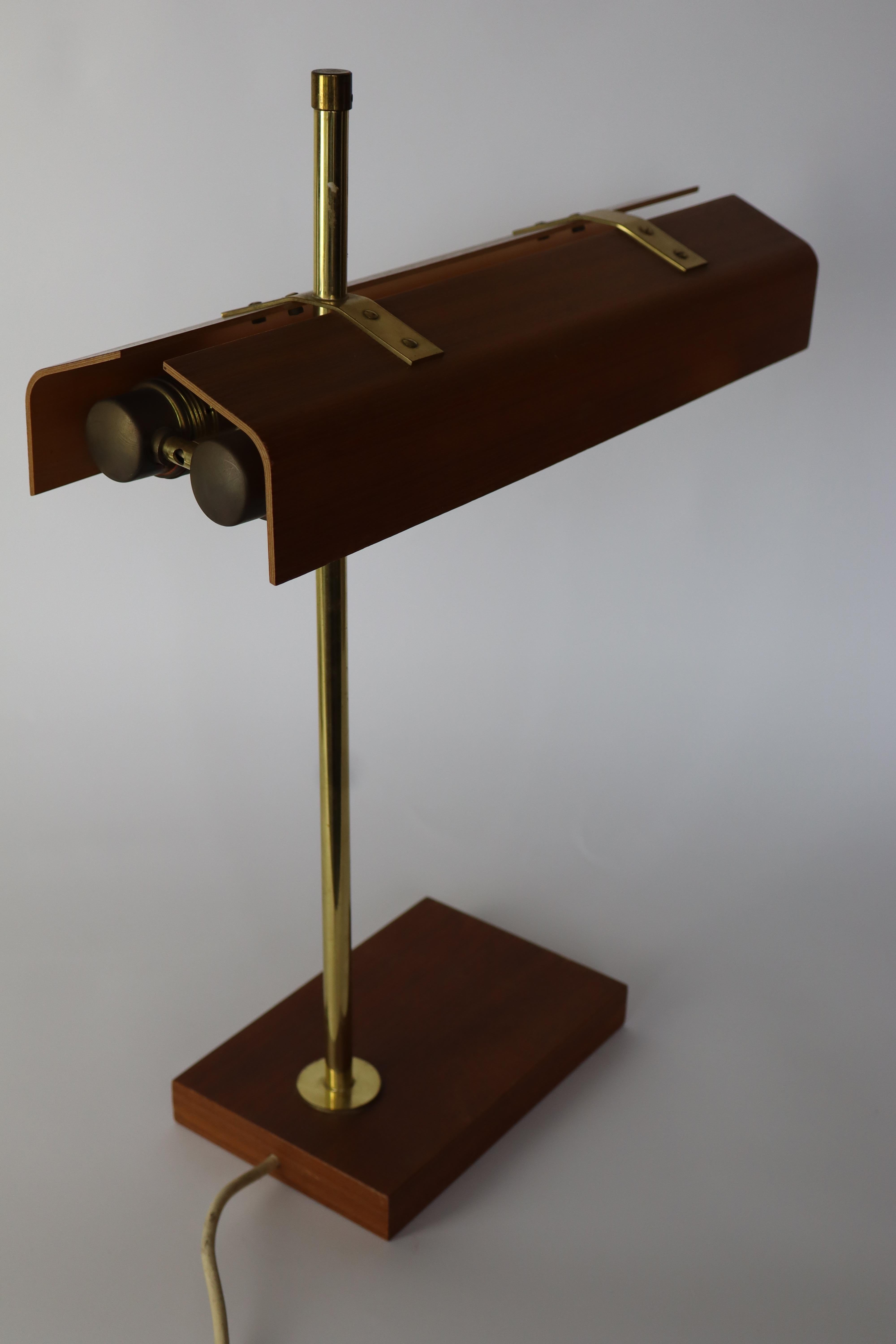1960's desk or tablelamp in plywood and brass.
Very similar to the German Kaiser leuchten desklamps in teakwood.

Foot is made in teakwood
Shade is made out of teak-plywood.
Very fine quality with nice brass details: for example, the visible screws
