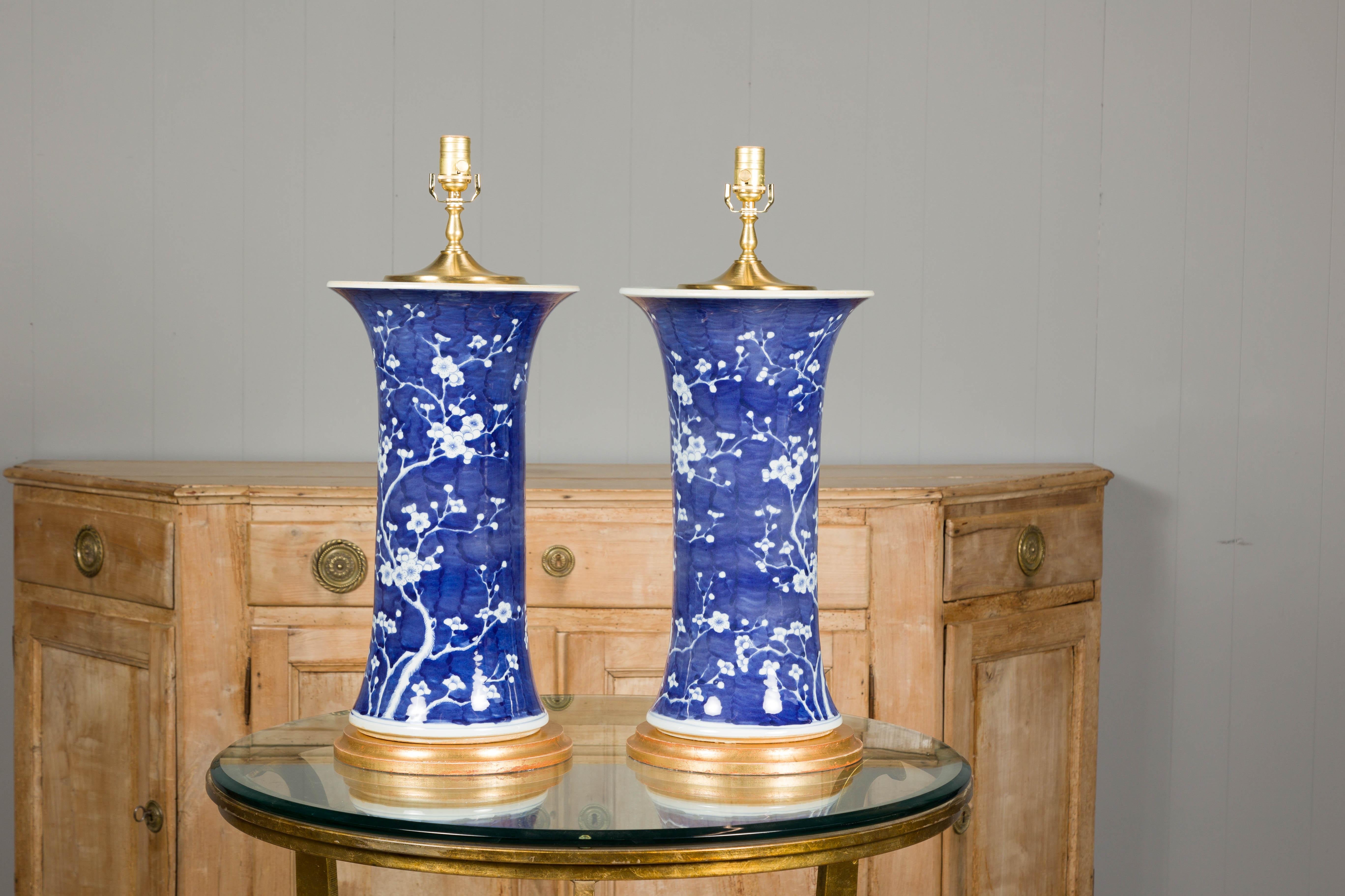 A pair of Midcentury Asian blue and white porcelain table lamps with floral décor on gilded bases, rewired for the USA. This pair of Midcentury Asian porcelain table lamps is a sublime blend of classic charm and modern functionality, designed to