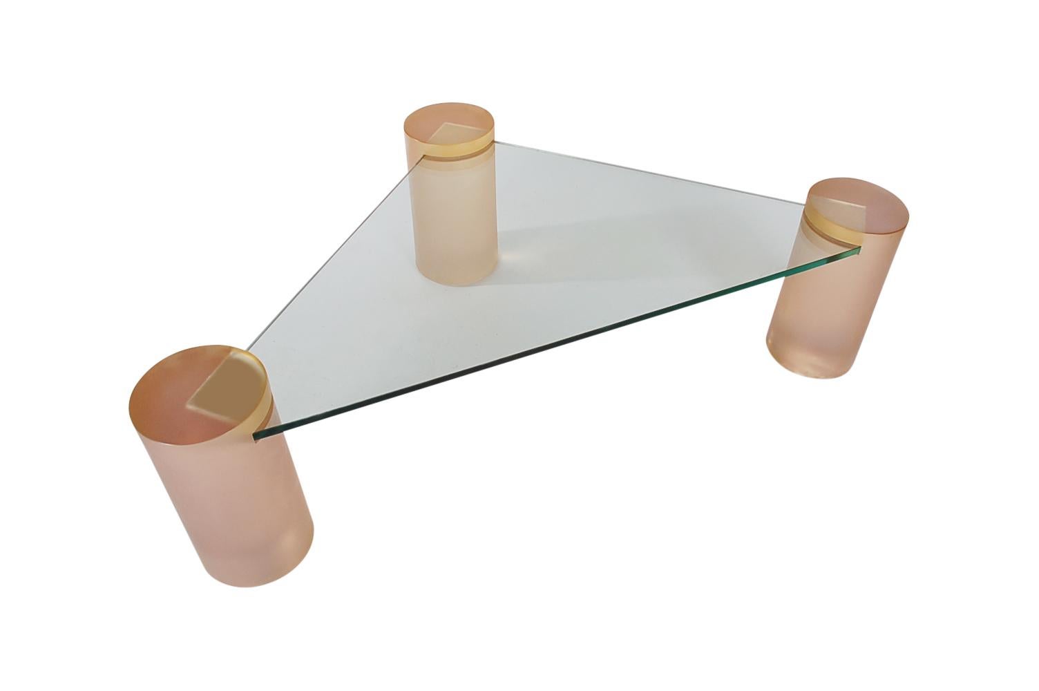 A super neat design from the 1980s. This table features three solid acrylic pedestals with a light blush pink color, and a floating piece of triangular glass.