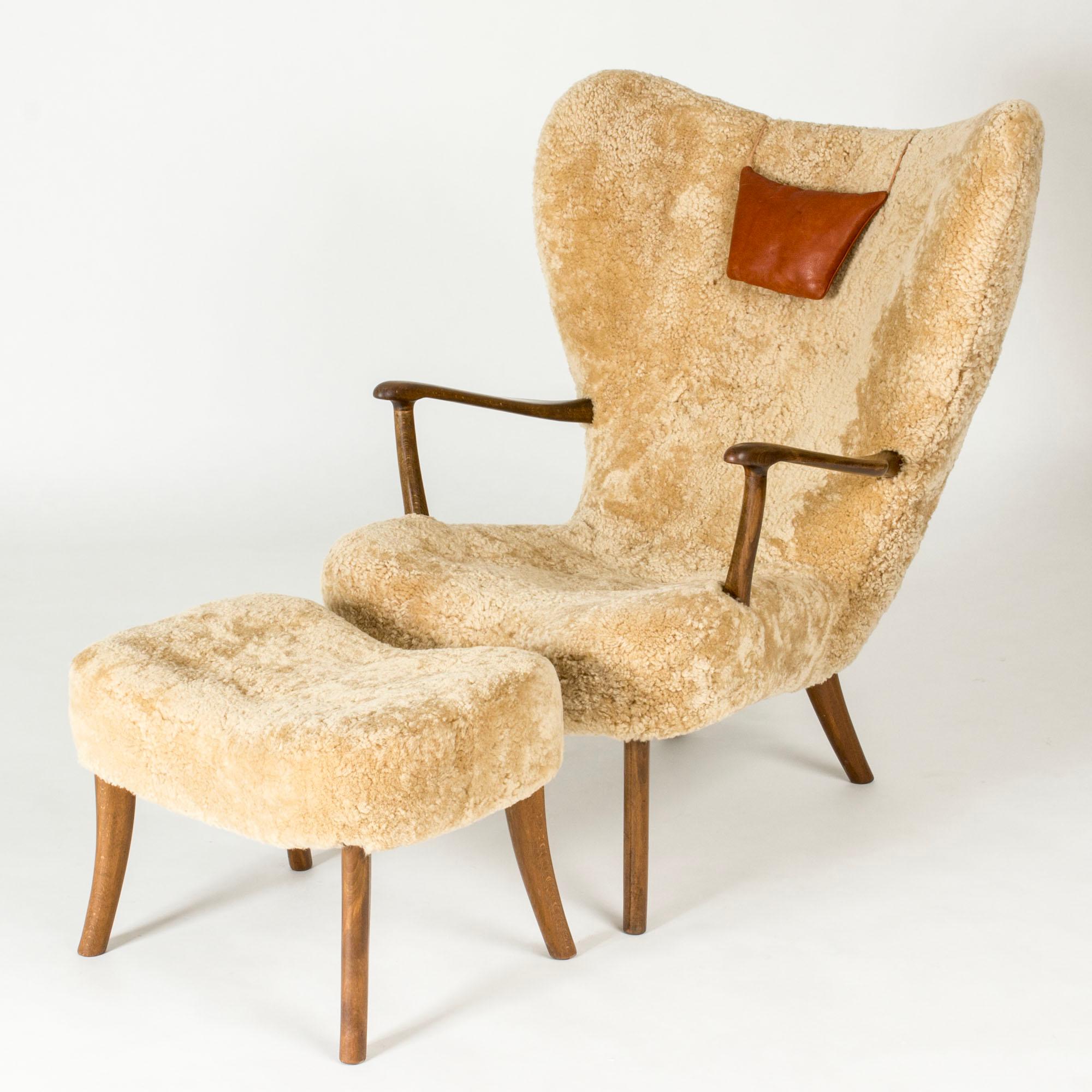 Elegant lounge chair and footstool by Ib Madsen and Acton Schubell, model called “Prag”. Made from beech with sheepskin upholstery. Generous size and lovely details, like the neck cushion and sculpted handles.

Stool height 42 cm
Stool width 60