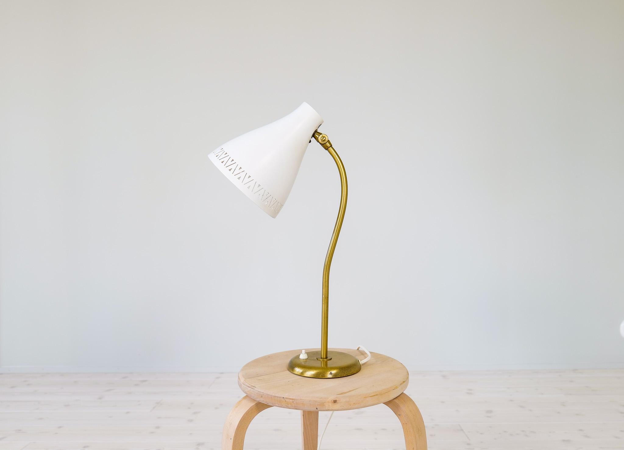 Wonderful large, and rare adjustable table lamp in brass, screen in white lacquered metal. Produced by Böhlmarks, Sweden, 1950s. The lamp shade gives a wonderful cozy light and that great impression of midcentury modern design. 

Good vintage