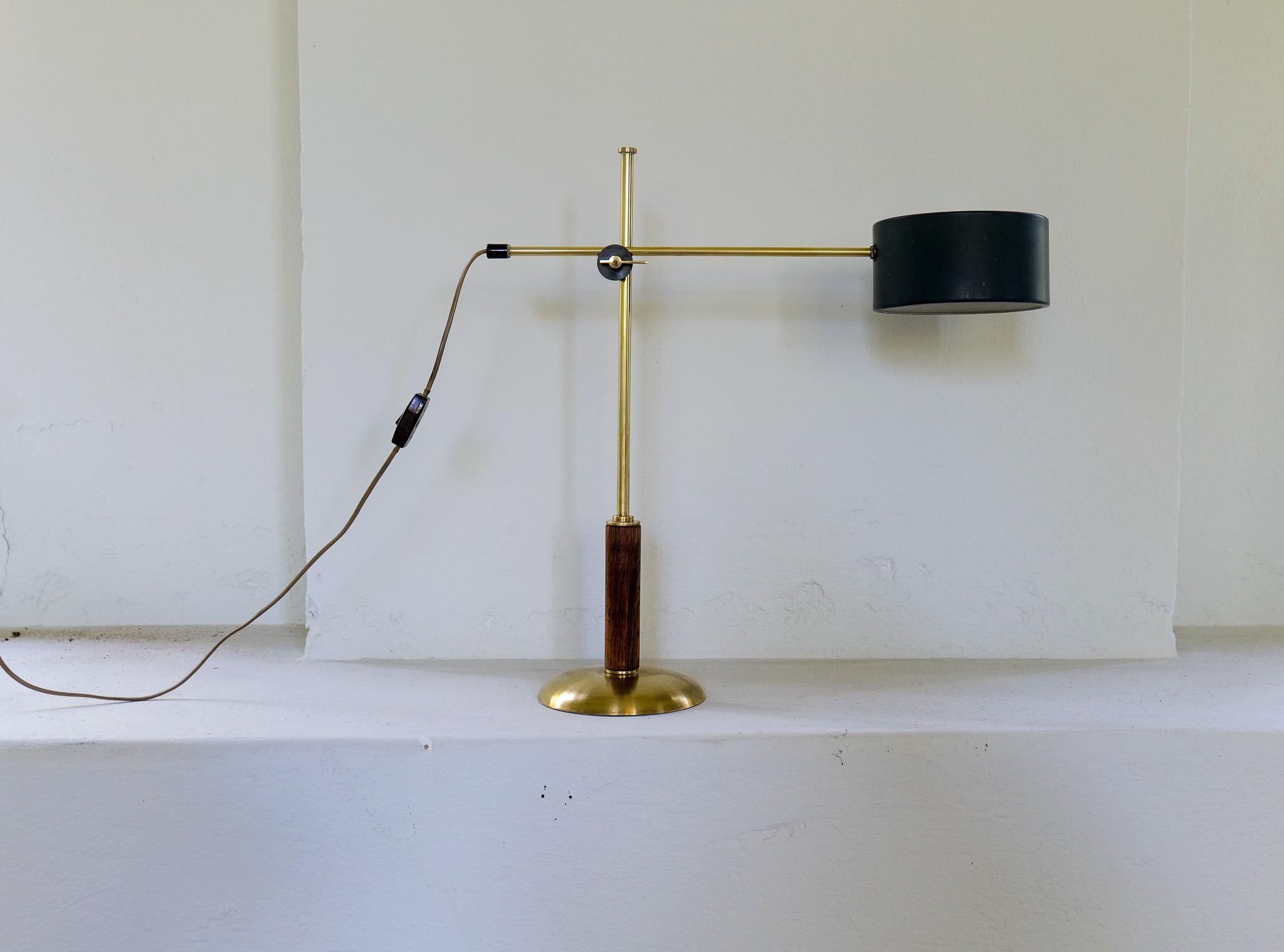 This rare table lamp produced in Sweden and designed by Einar Bäckström is adjustable in both height and angles. 
Brass base with walnut rod and a lacquered shade with brass details. 

Good vintage condition with some wear to the shade.