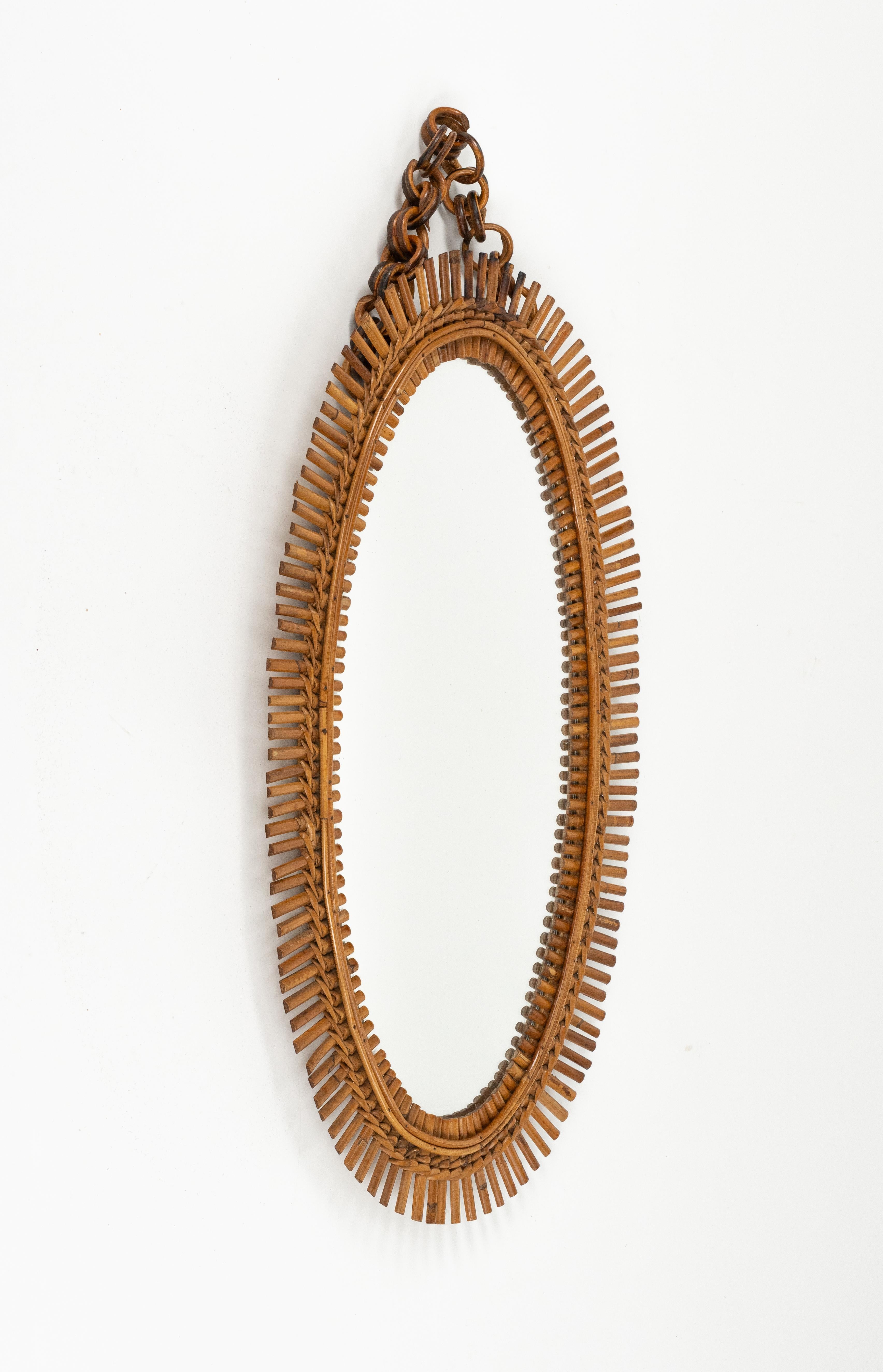 Midcentury beautiful oval wall mirror with chain in bamboo and rattan in the style of Franco Albini.

Made in Italy in the 1960s.   

A highly decorative mirror.   

Dimensions without chain:  
Height 72 cm.  
Width 44 cm.  
Depth 3.5 cm.