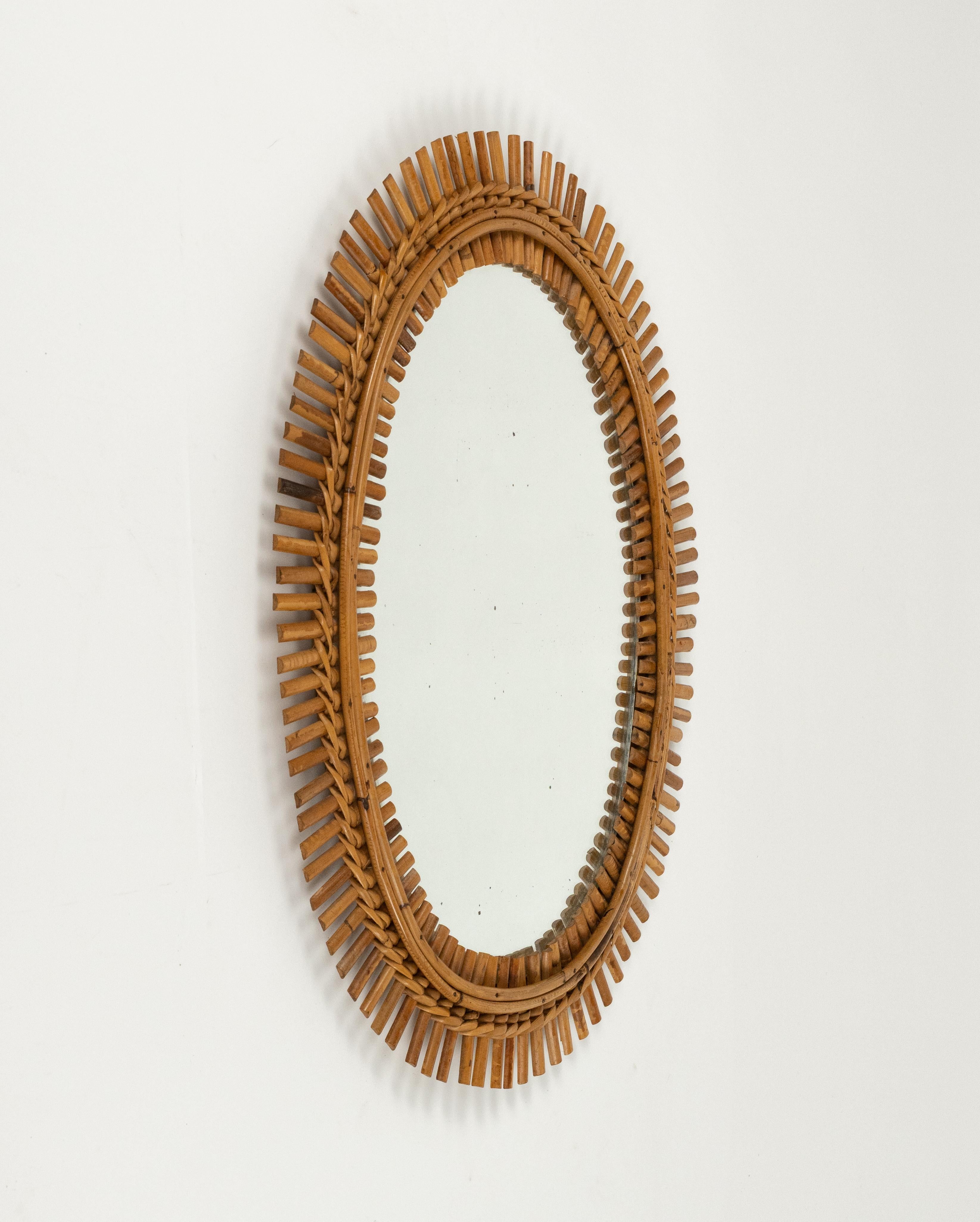 Midcentury beautiful oval wall mirror in bamboo and rattan in the style of Franco Albini.   

Made in Italy in the 1960s.   

A highly decorative bamboo and rattan mirror with the taste of the Mediterranean Coast style. 