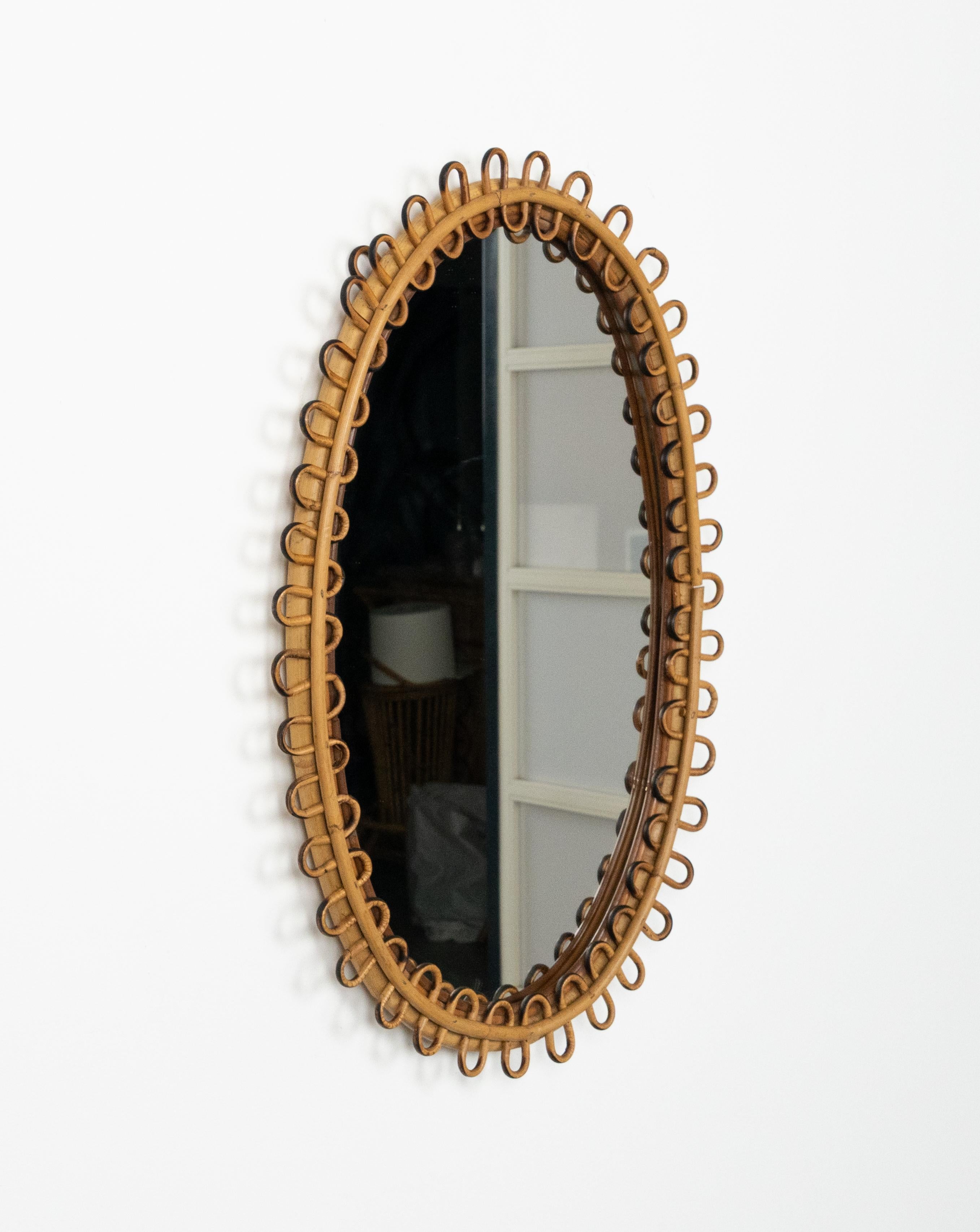 Miroir mural ovale en bambou et rotin dans le style du design italien Franco Albini.  

Fabriqué en Italie dans les années 1960.  

Un miroir en bambou et rotin très décoratif au goût de la côte méditerranéenne.