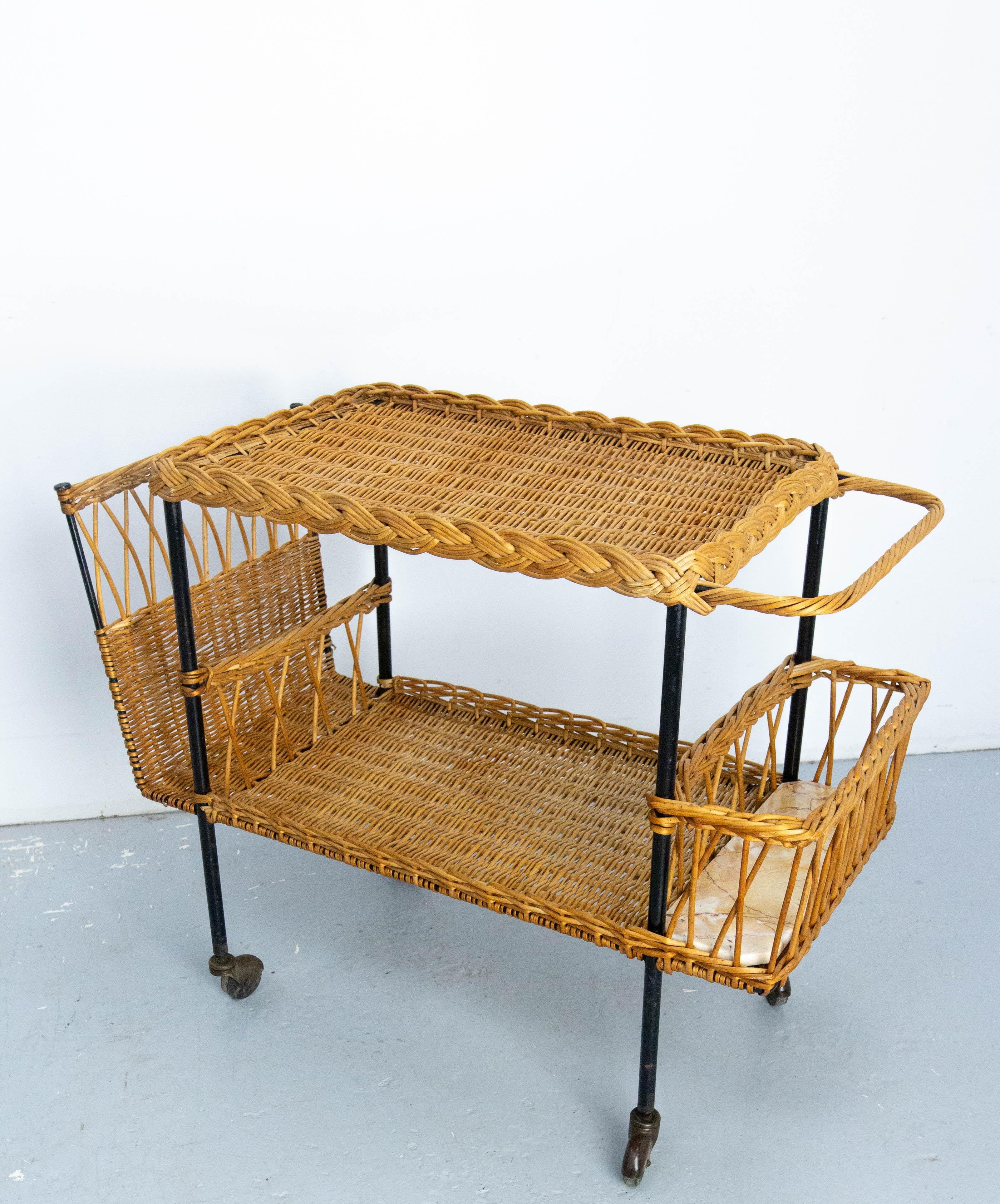 Rattan and black  metal serving trolley bar cart drinks midcentury, made circa 1950.
Raoul Guys is a Parisian interior designer who will produce some furniture typical of the 1950s style. His favorite materials were rattan and metal.
This trolley is