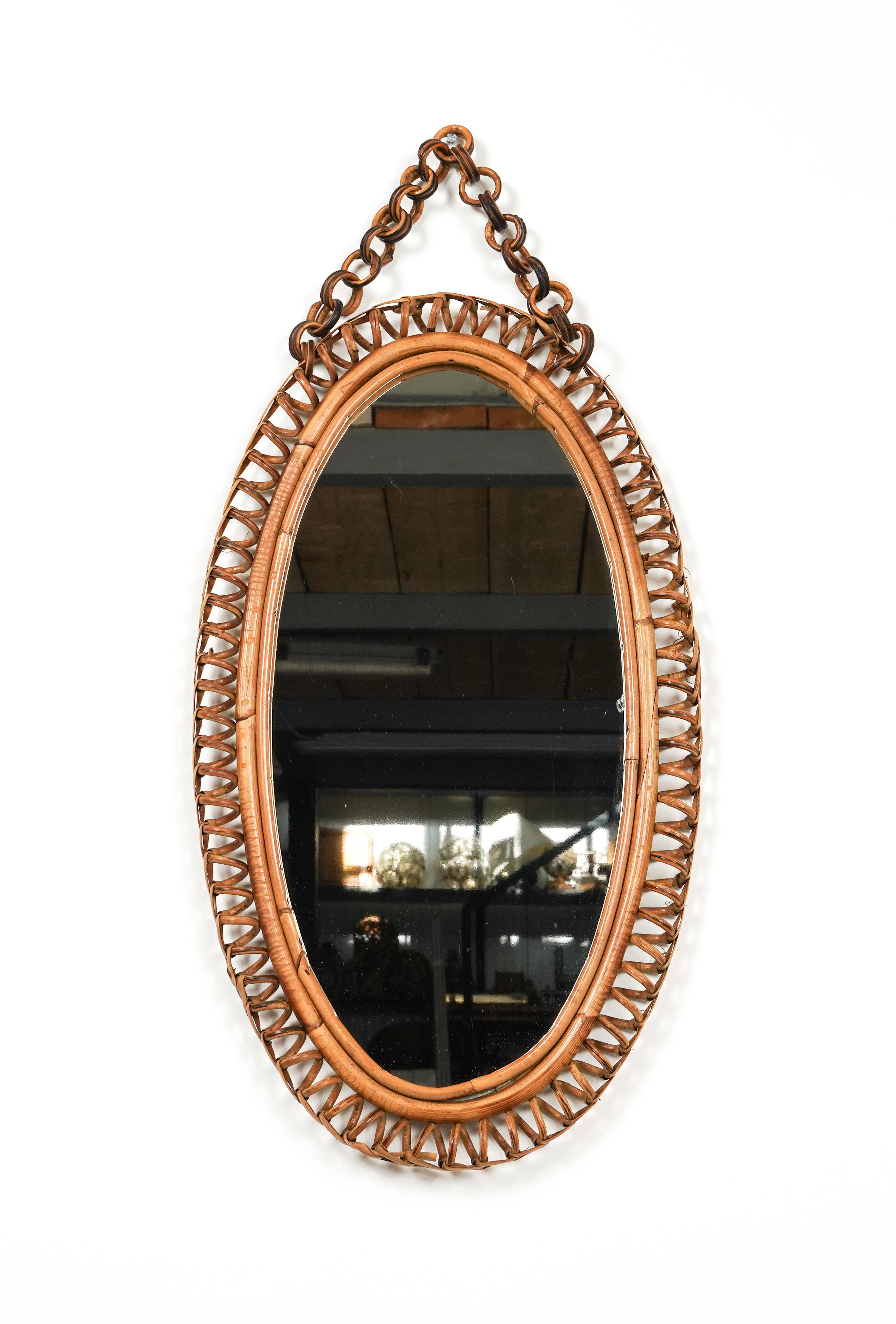 Midcentury beautiful oval wall mirror with chain in bamboo and rattan in the style of Italian design Franco Albini.

Made in Italy in the 1960s.

A highly decorative mirror.

Dimensions without chain:
Height 70 cm.
Width 40cm.
Depth 3cm.