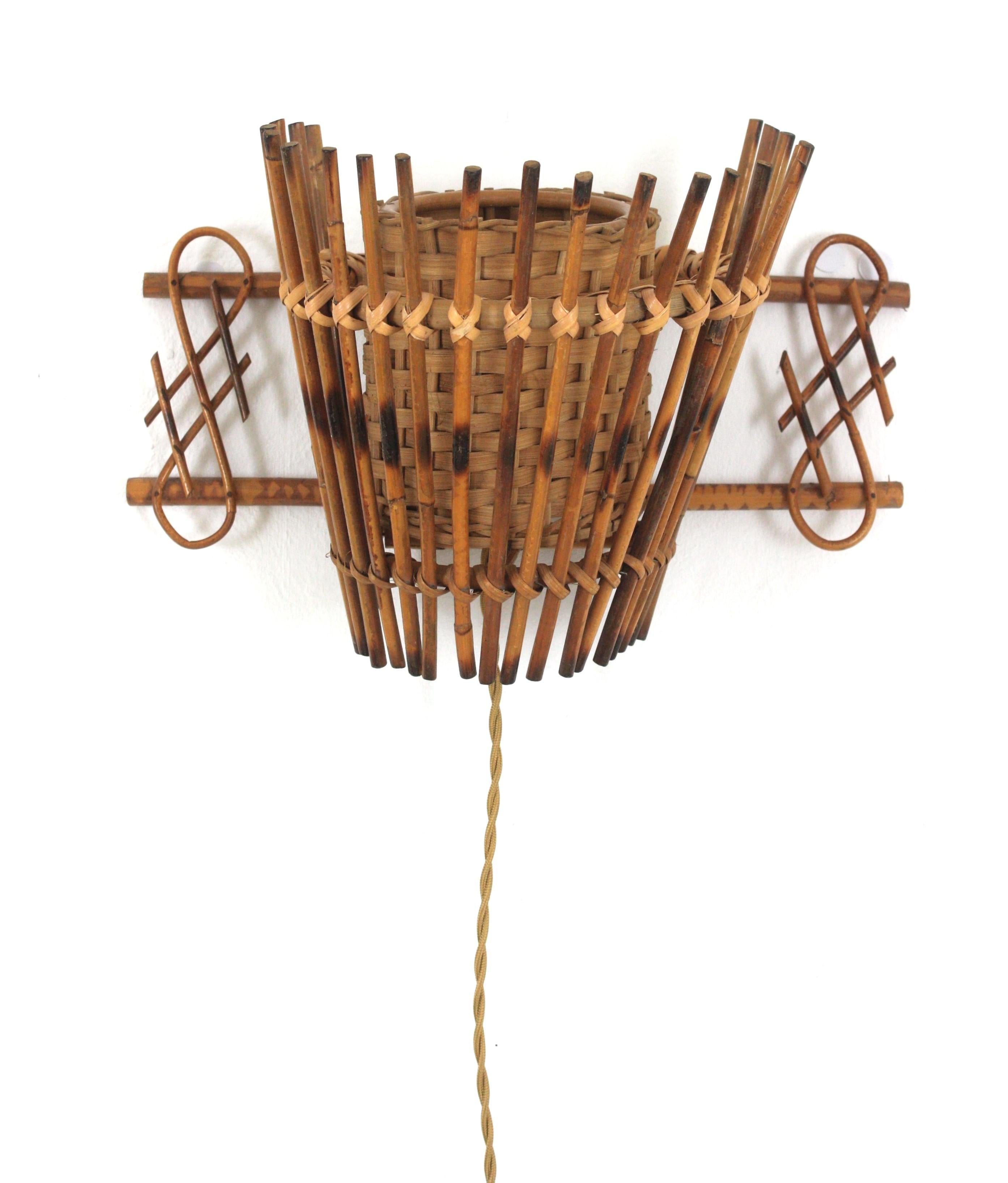 Mid-Century Modern Wall Sconce in Rattan and Woven Wicker. France, 1950s.
This French Riviera conical rattan wall light has an eye-catching design with chinoiserie decorations at both sides. It has an interior woven wicker cylinder lampshade to