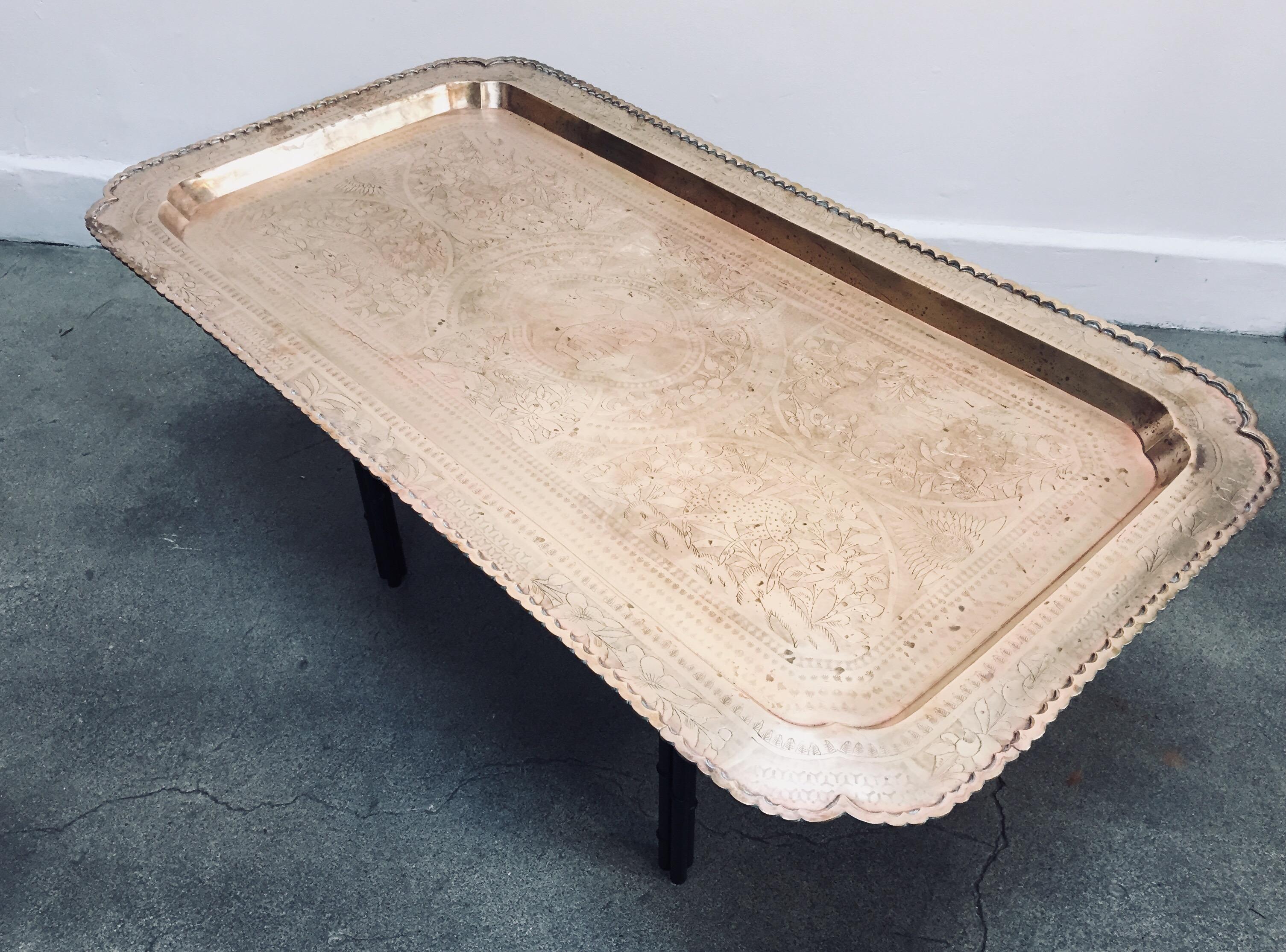 Hollywood Regency style, midcentury brass tray table with etched rectangular brass tray.
Sit on a metal faux bamboo base in black color.
Made in Honk Kong with Chinese design and scenes of animals.
Measures: Base 14