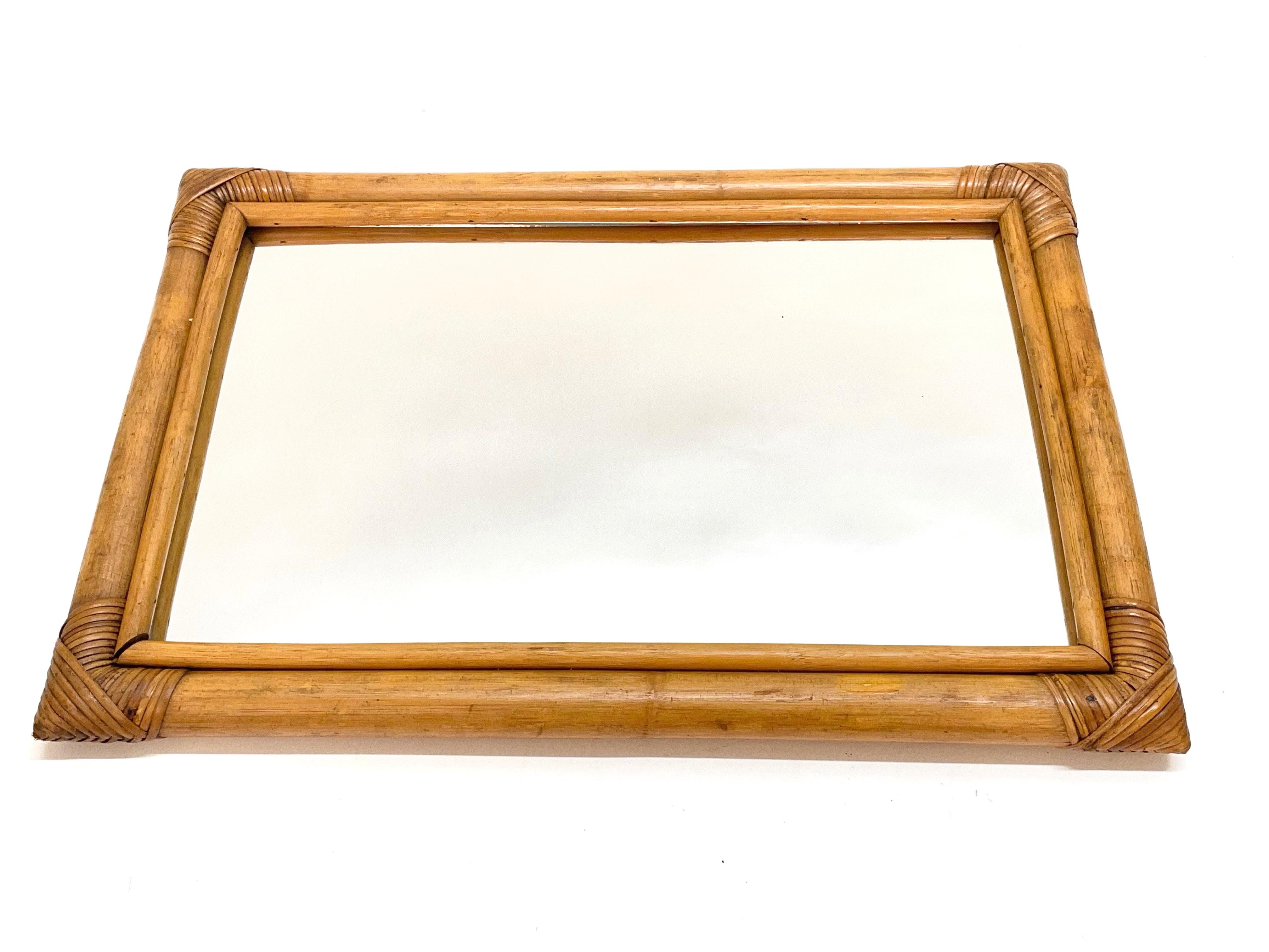 Wonderful midcentury rectangular mirror with a double bamboo cane weaved wicker frame. This amazing item was produced in Italy during the 1960s.

The way in which bamboo lines and glass integrate is superb and coveys neverending charm to this