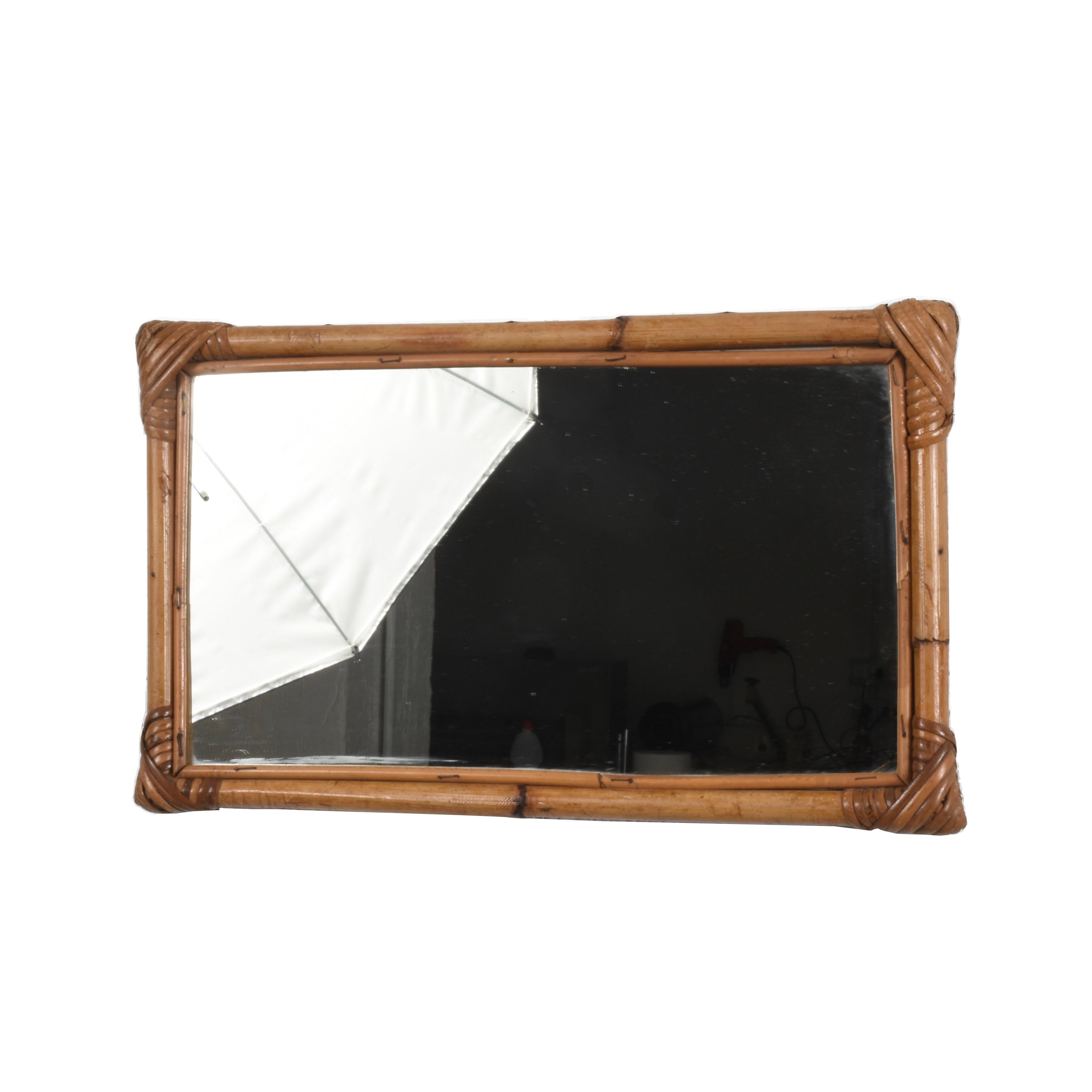 Marvelous midcentury rectangular mirror with double bamboo cane frame. This fantastic item was produced in Italy in the 1970s.

The way the straight lines of the bamboo integrate with the mirror. The corners, made of rattan and connecting the