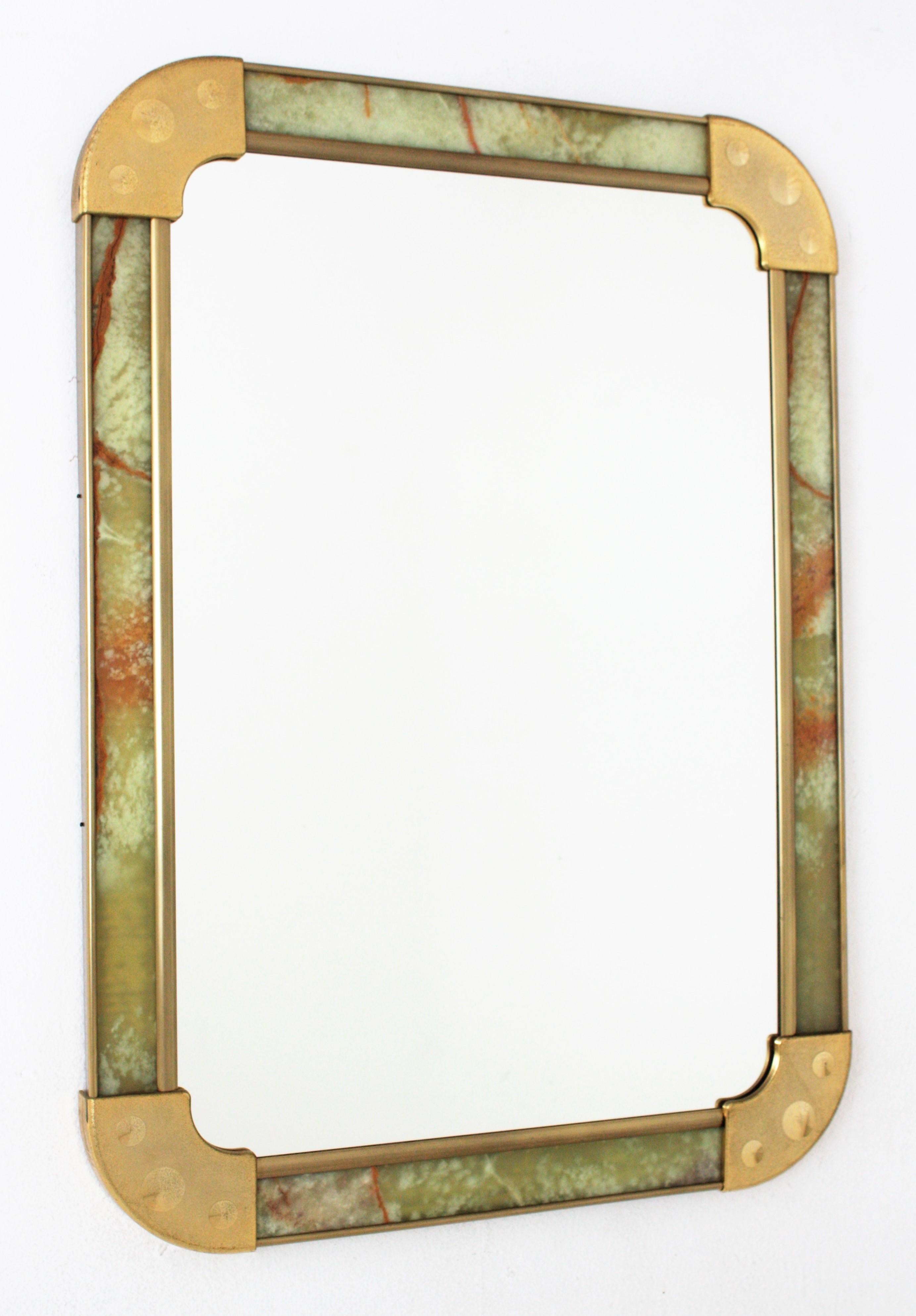 Rectangular wall mirror with onyx frame and gilt metal accents, Spain, 1960s-1970s.
This wall mirror has a rectangular frame made with onyx panels and gilt acrylic rounded corners and brass accents surrounding the onyx panels. 
The onyx veins in