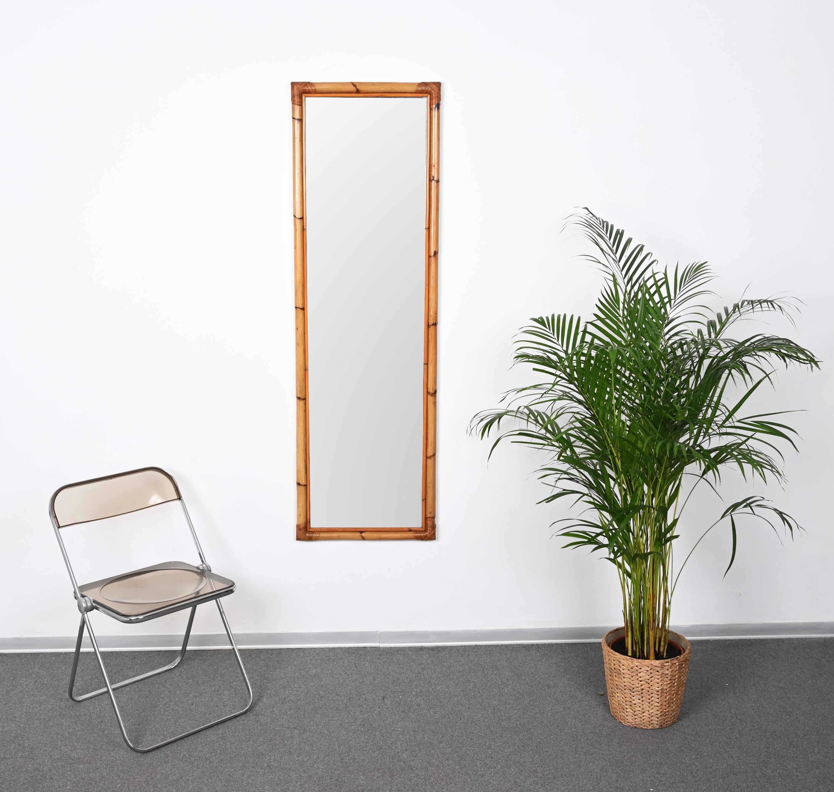 Stunning full lenght midcentury rectangular bamboo and woven wicker mirror. This gorgeous piece was designed in Italy during the 1970s.

This sturdy mirror has a wonderful double frame in bamboo with the corners decorated with beautiful weaved