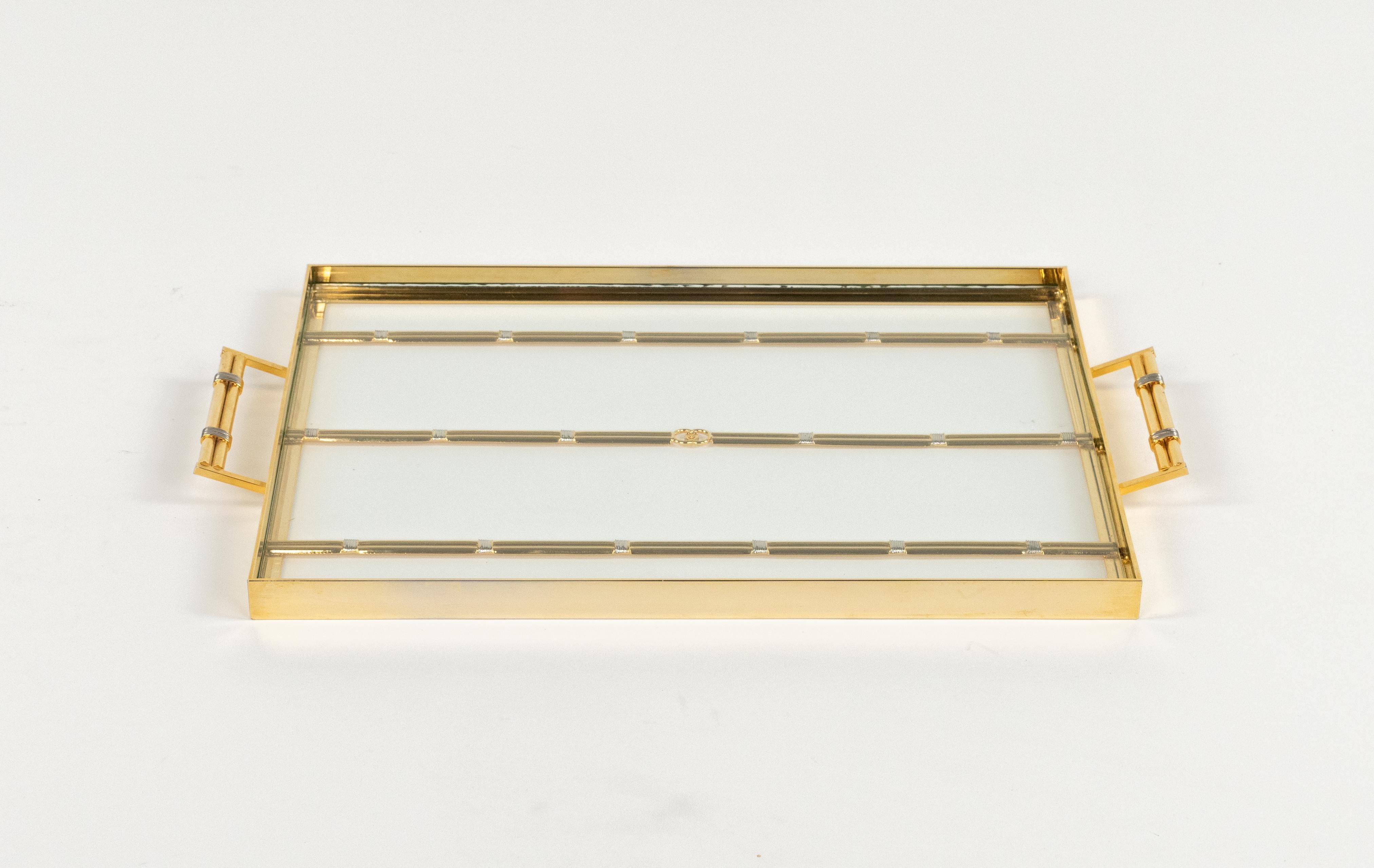 Magnifique plateau de service rectangulaire du milieu du siècle en laiton et verre avec des bandes argentées par Gucci.

Fabriqué en Italie dans les années 1970.

Le plateau est signé comme le montrent les photos.

C'est un plateau emblématique  en