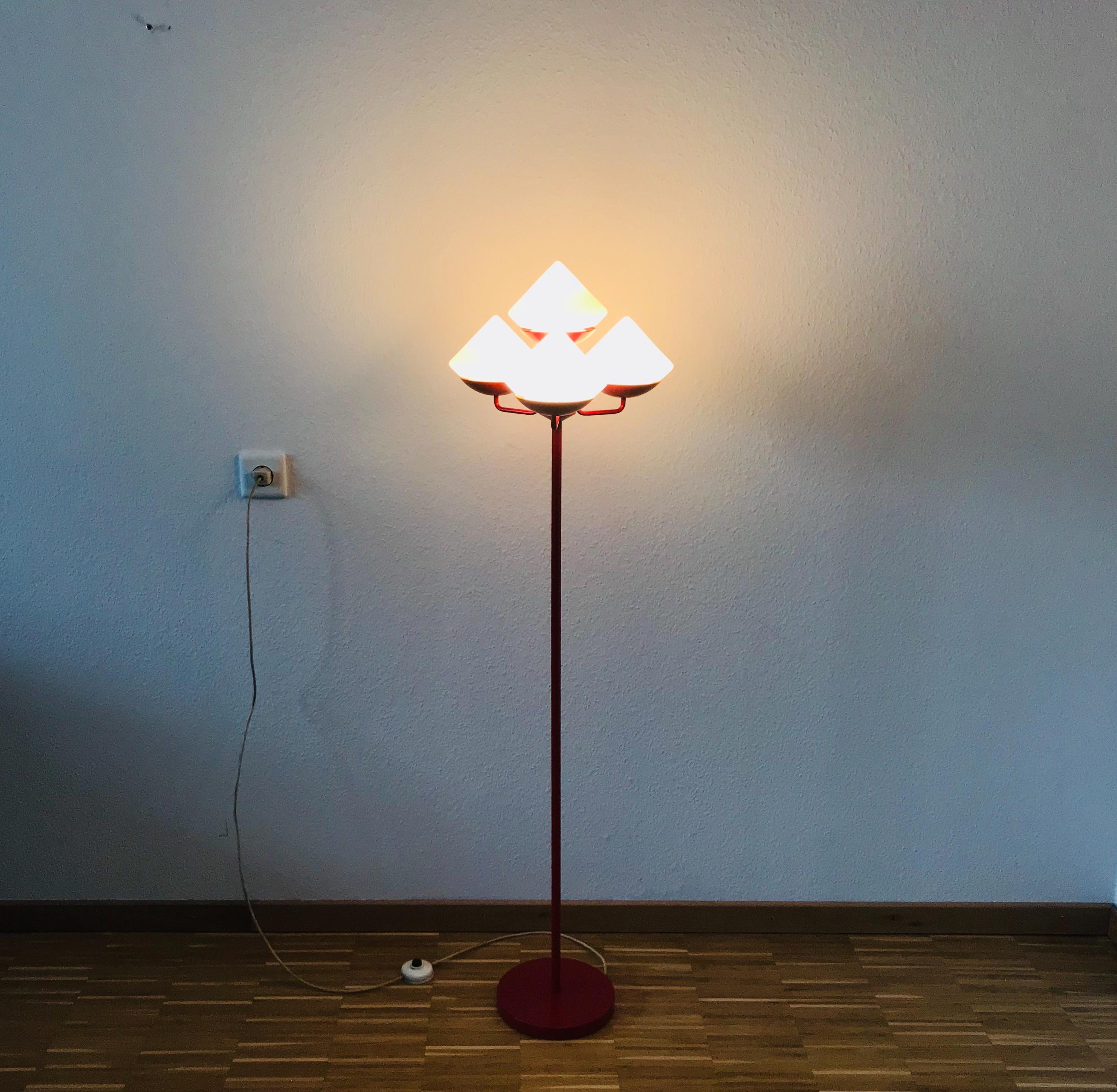 A midcentury floor lamp attributed to Kaiser made in Germany in the 1960s. It is fascinating with its Space Age design and four cone shaped opaque balls. The bottom of the light is made of full metal. The bar is also made of metal including the
