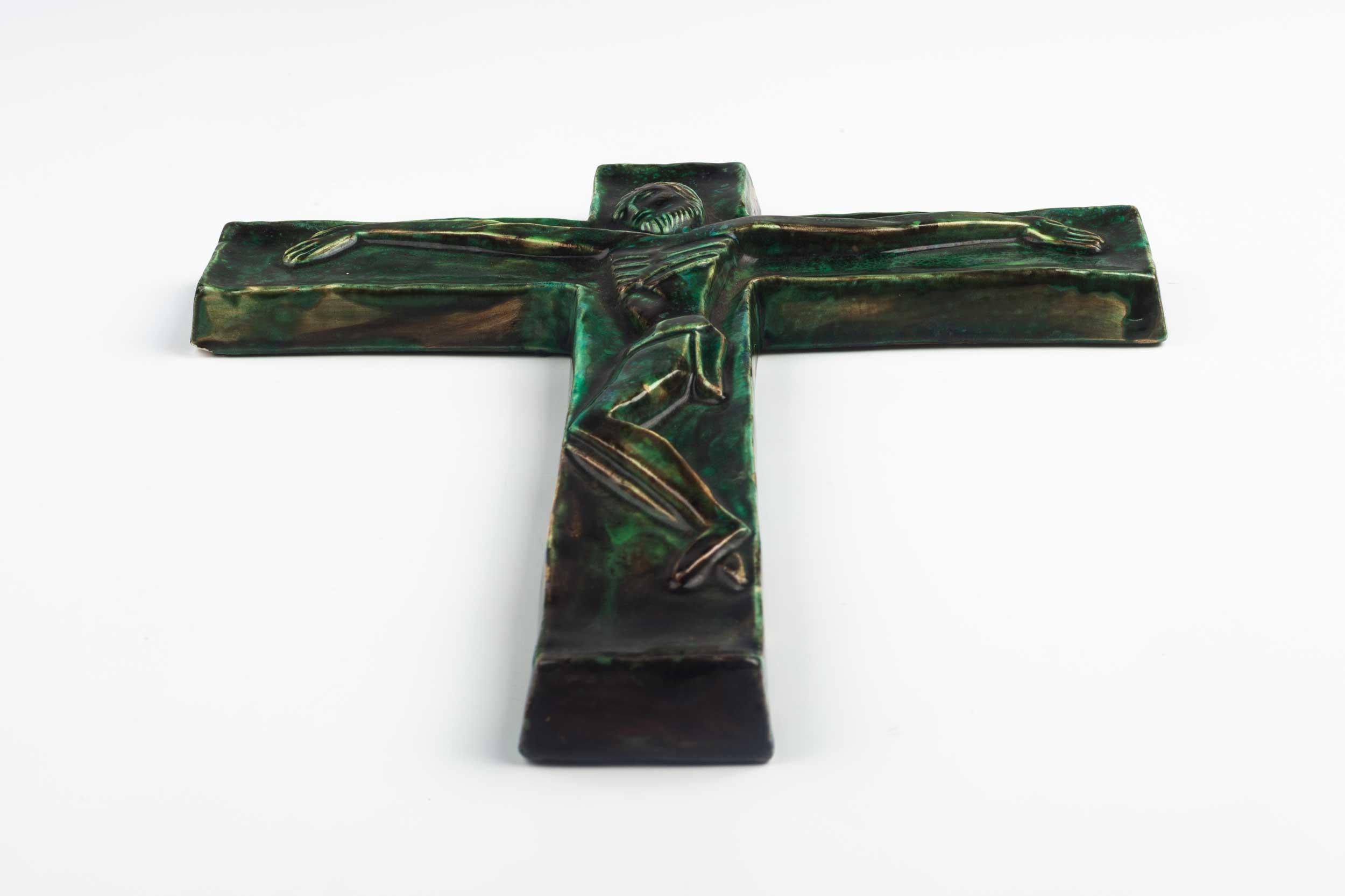 Midcentury European wall crucifix in glazed, hand painted green ceramic depicting stylistic Christ on green cross. From a large collection of vintage crosses handmade by Flemish artisans. 

From modernism to brutalism, the crosses in our