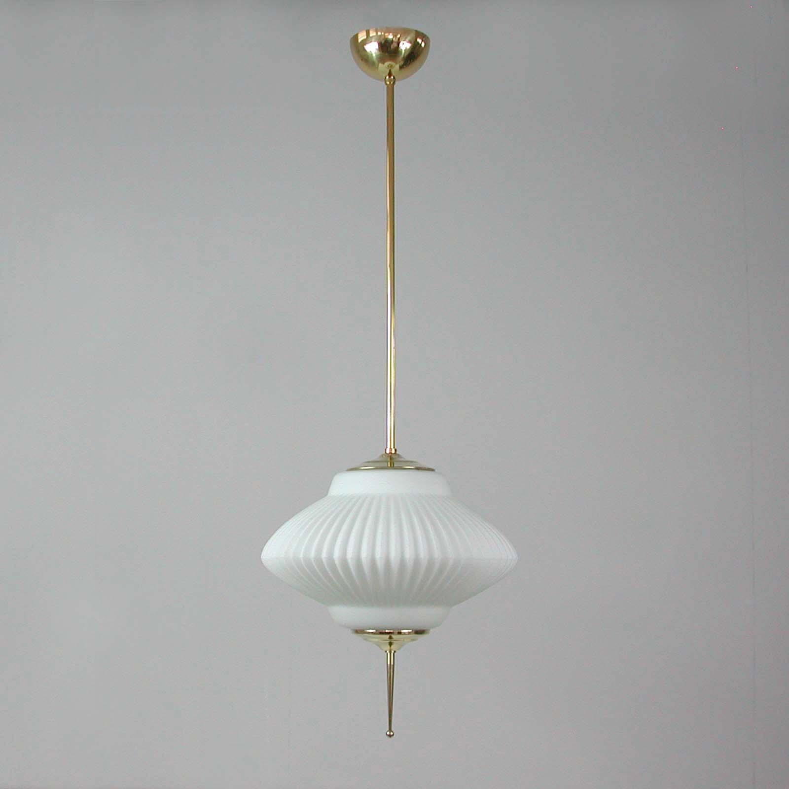 This midcentury lantern was designed and manufactured in Italy in the 1950s to 1960s. It features a ribbed milk glass globe with brass hardware and a brass canopy. 

A simple, elegant and timeless design. 

The lamp has been rewired for use in