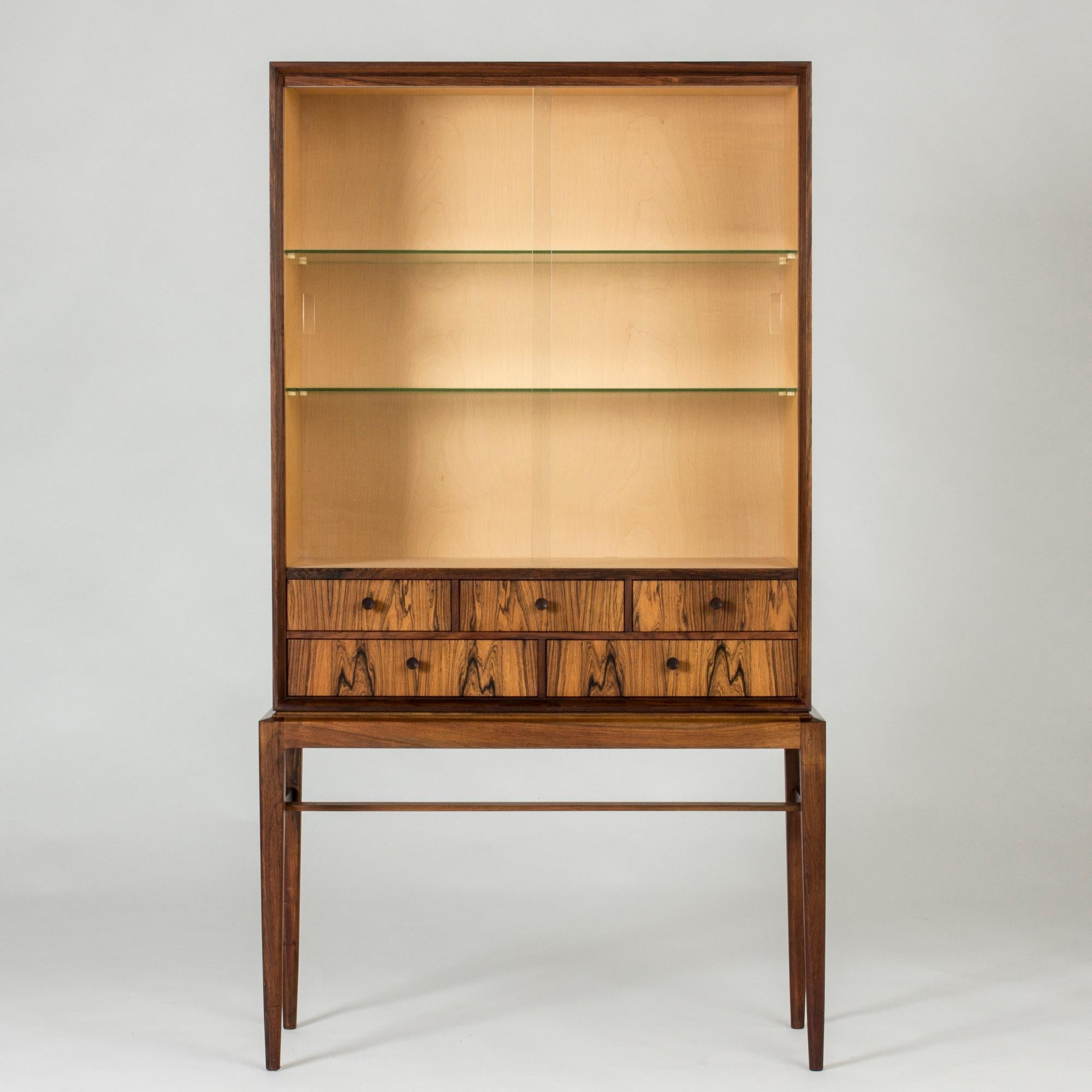Elegant rosewood cabinet with vitrine doors and glass shelves by Svante Skogh. Small drawers with beautiful woodgrain. Slender legs give the cabinet a light expression.