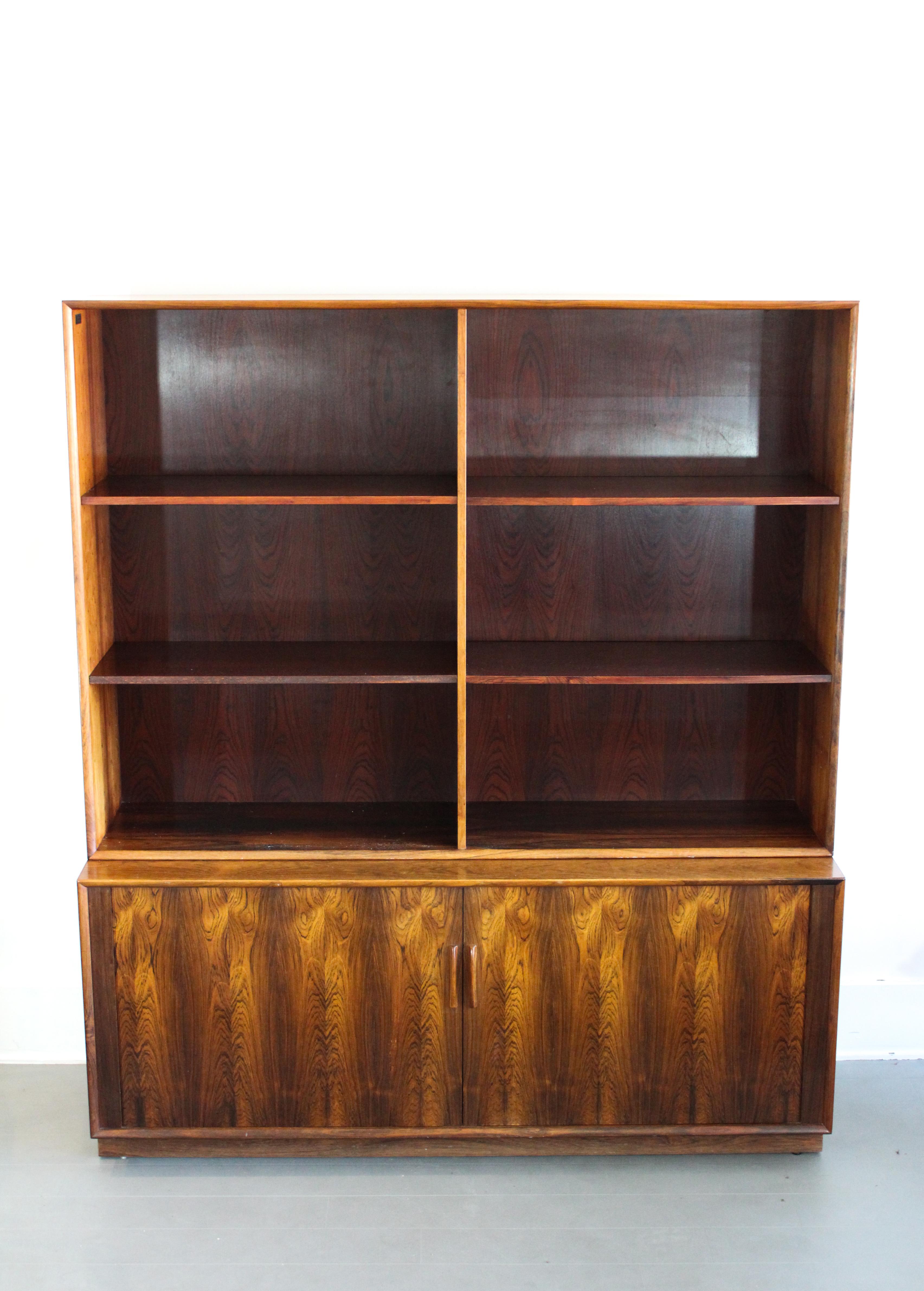 A rare bookcase designed by Arne Vodder for Danish manufacturer Sibast Møbler. This piece has a one lower cabinet with sliding tambour doors and a book case upper part, all made out of rosewood. It is in good vintage condition with fully functional