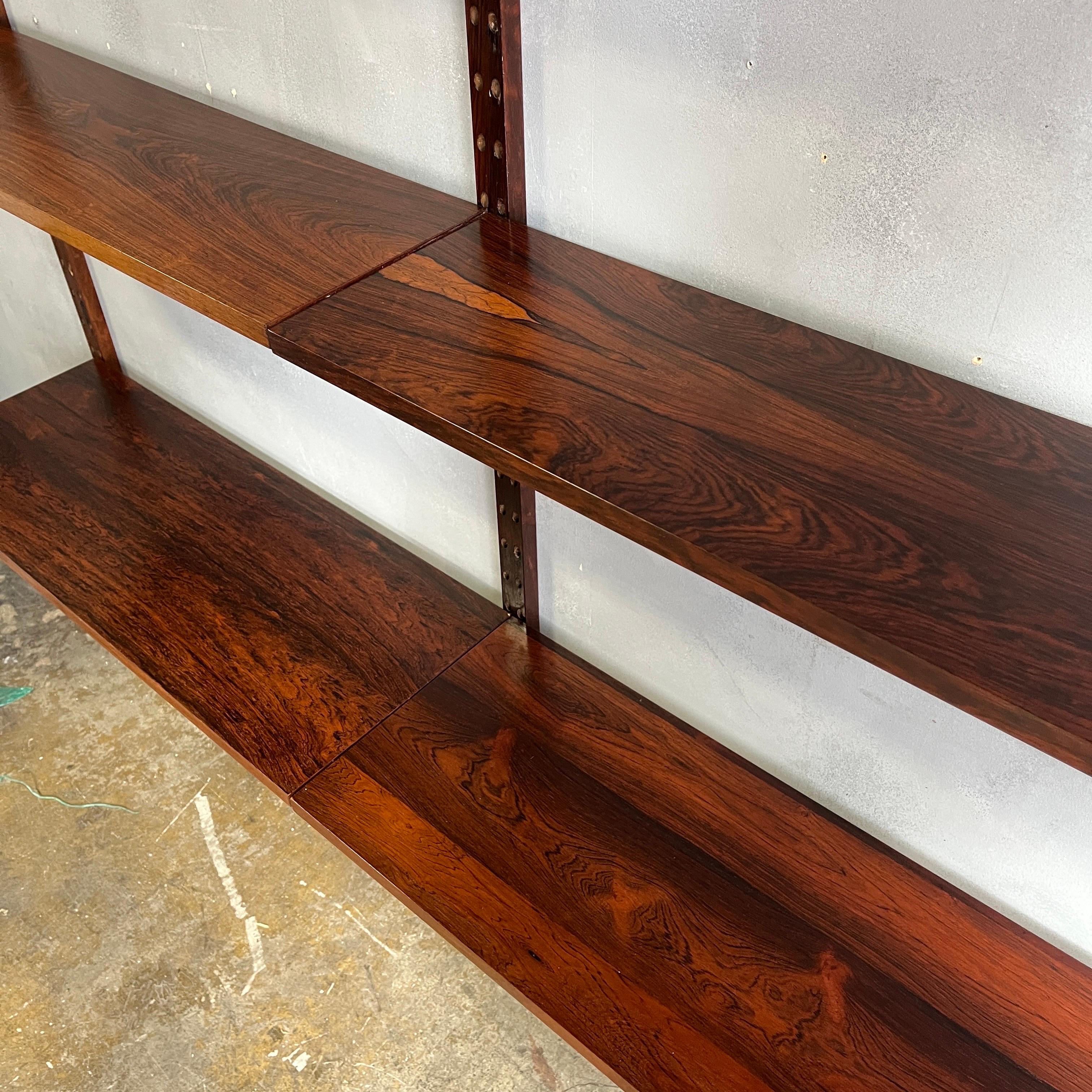 Beautiful rosewood variations on this Cado wall unit. Featuring 8 x 9'' and 2 x 12'' shelves ( 10 total ). A two bay bookcase / wall unit that can be infinitely adjusted by utilizing the peg hole system along the full 80'' length rails. We love the