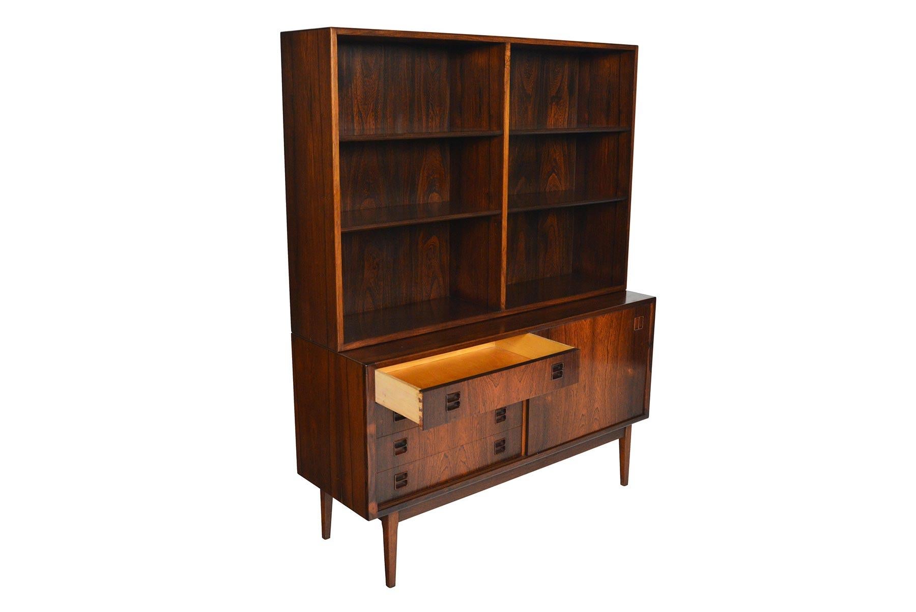 Wonderfully adaptable, this Danish modern rosewood credenza features a removable bookcase hutch. The credenza offers a cabinet with two adjustable shelves and a bank of four drawers. The two bay hutch is outfitted with four adjustable shelves. In