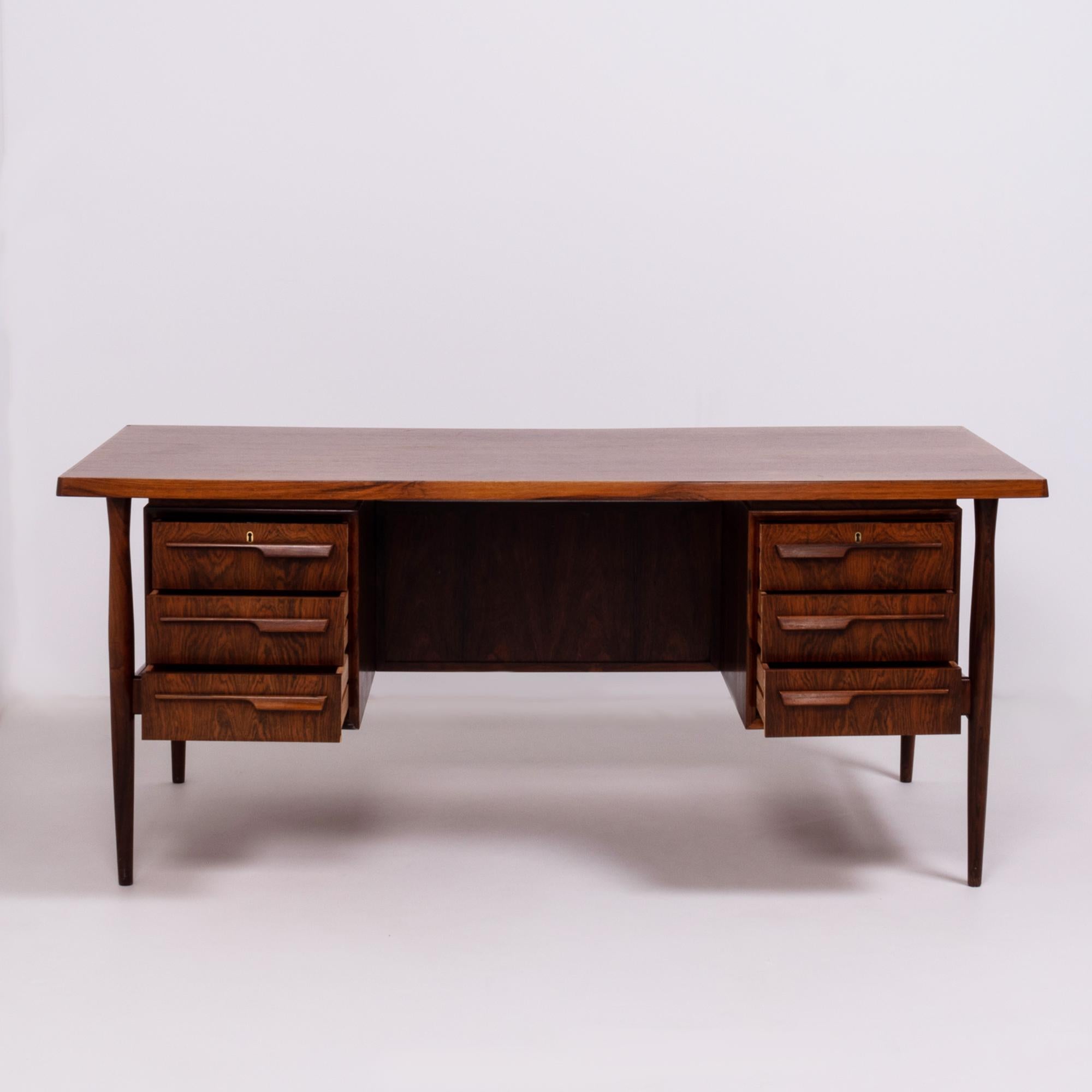 Beautifully constructed in rosewood, this large solid desk is a wonderful example of Mid-Century Modern design

Offering plenty of storage options, the front of the desk has two sets of three drawers, while the back of the desk has an open shelf