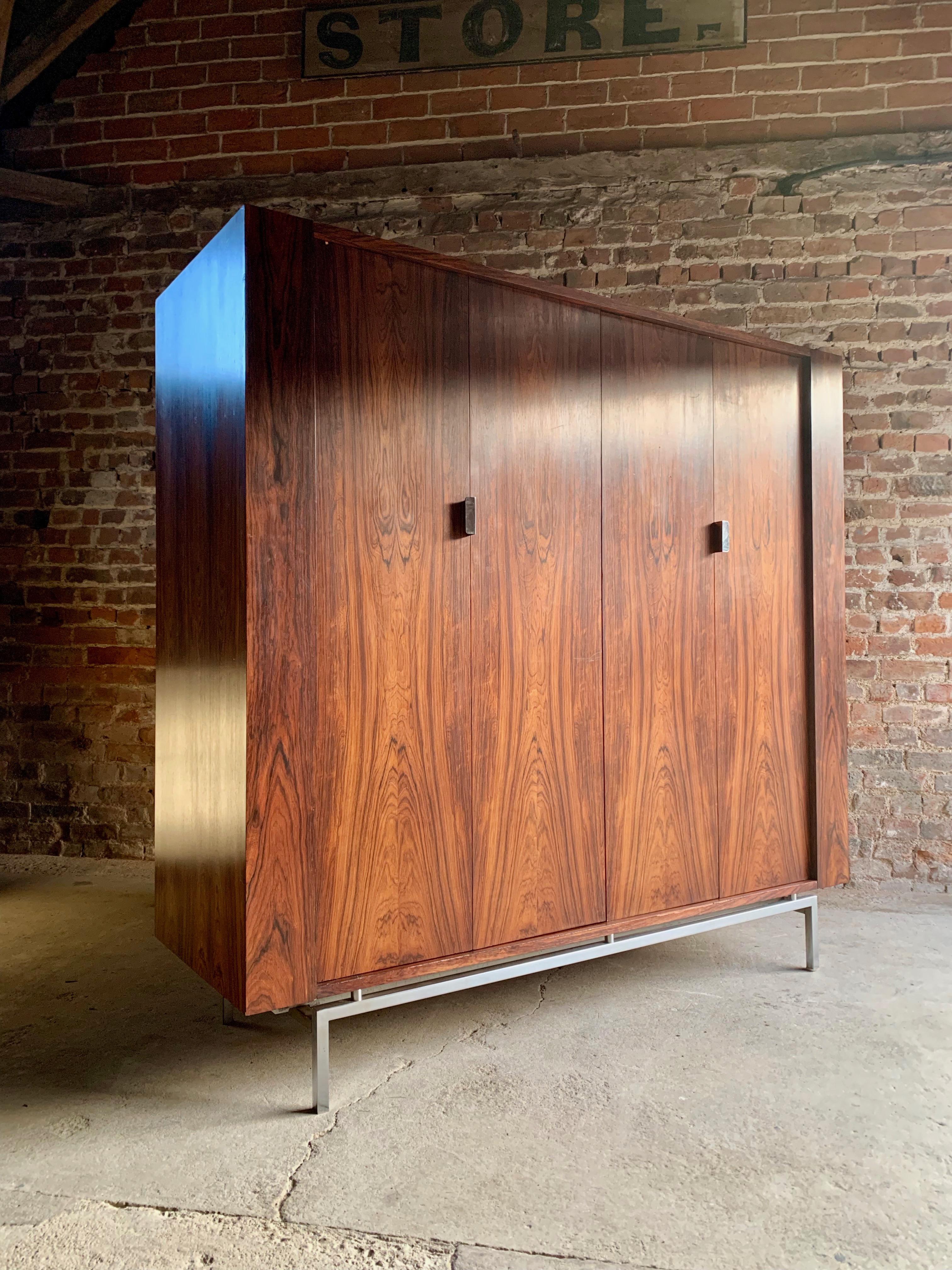 A stunning midcentury rosewood armoire wardrobe circa 1970, fitted with three adjustable shelves and hanging compartment enclosed by pair of concertina-action doors with chrome metal handles, raised on chrome-finish square legs.

Please note: the