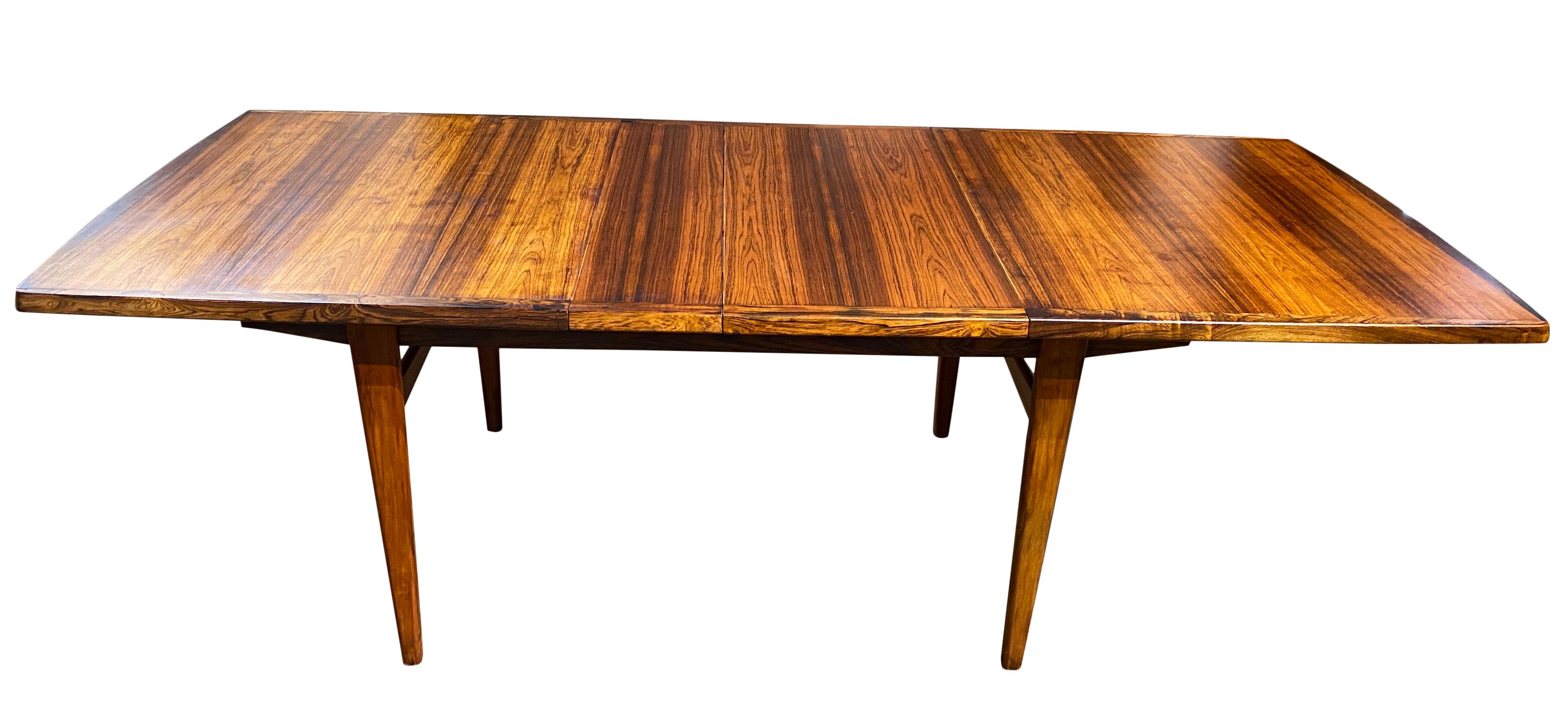 Stunning Midcentury rosewood expandable dining table with 2 nesting leaves. This is a beautiful dining table Made in Denmark. Amazing solid rosewood legs and Woodwork on table is beautiful. Made, circa 1960. Original finish in excellent condition.